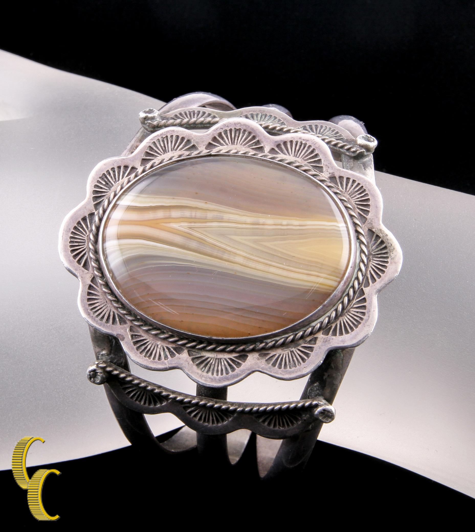 Gorgeous 0.925 sterling silver cuff bracelet.
Vintage Native American, Hopi or Zuni.
Center features an oval brown agate with nice caramel striations.
Center stone: 40 x 30 mm.
Wrist Fit: 6.25 inches.
Hallmark: 925
Weight: 63.6 grams.