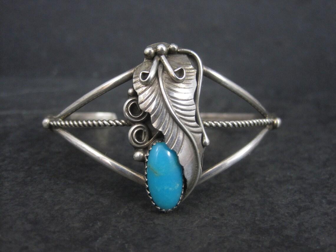 This gorgeous, dainty Native American cuff bracelet is sterling silver with a turquoise gemstone.
It is the creation of Navajo silversmith Herman Lee.

The face of this cuff measures 1 5/16 inches north to south.
It has an inner circumference of 5