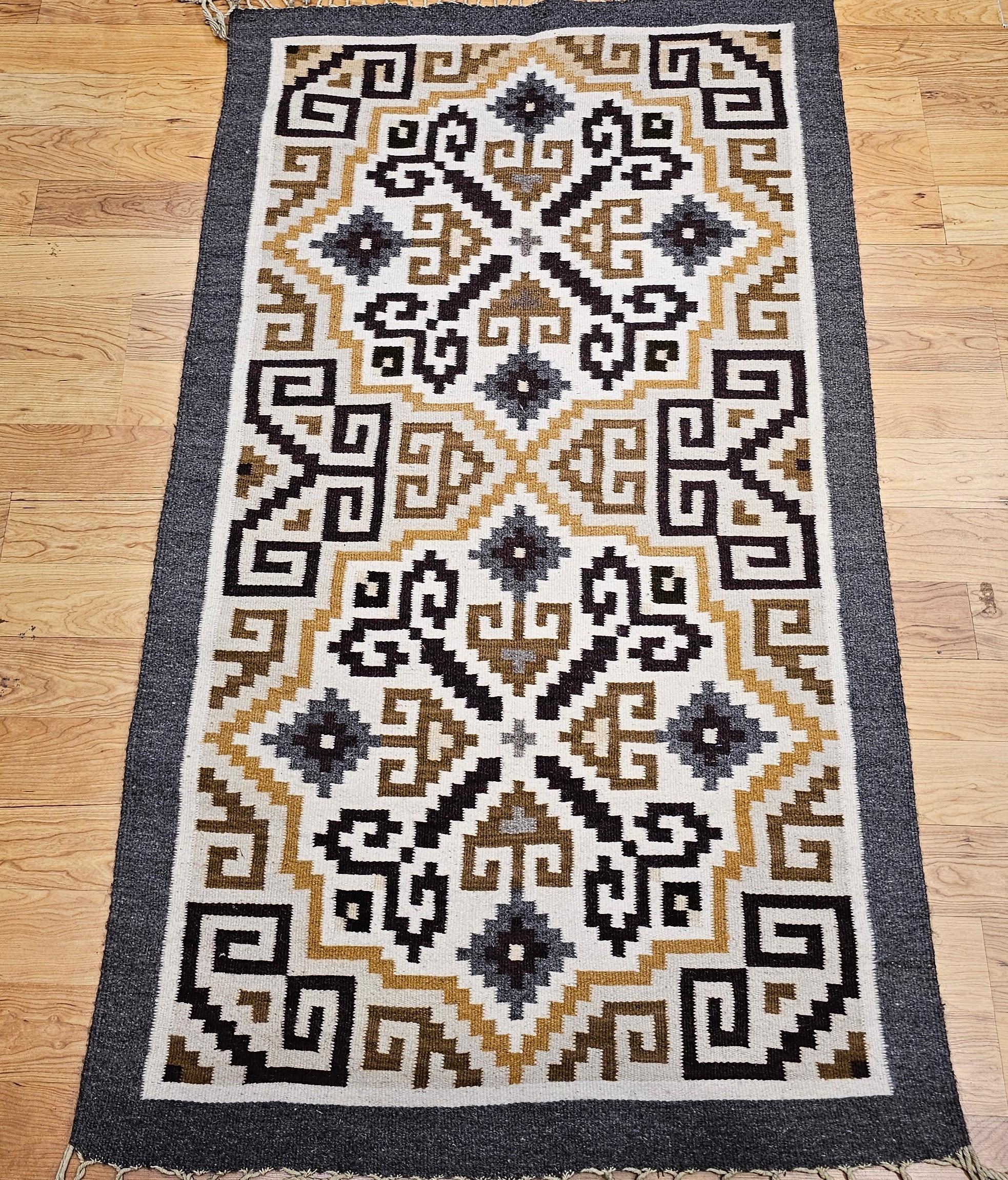 Eleva tu espacio con la refinada belleza de esta alfombra navajo vintage Two Grey Hills, con una paleta atemporal de tonos tierra como el marfil, el marrón, el negro y el gris. Tejida a mano en el suroeste de Estados Unidos, esta alfombra