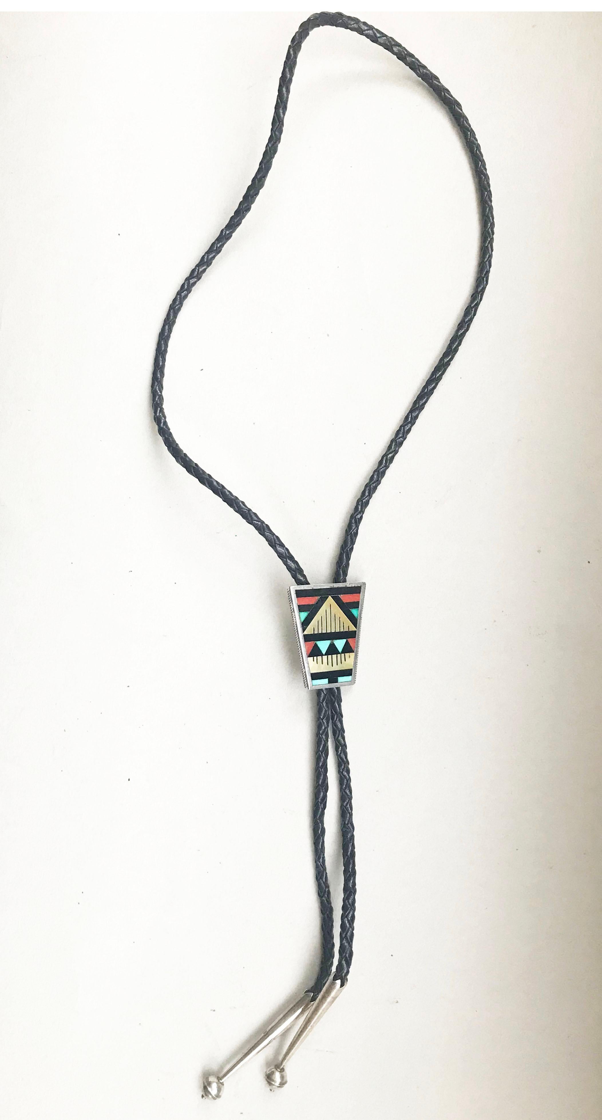 A handsome hand-crafted Zuni Bolo tie in sterling silver with natural stone inlay 
Circa 1960s.
With plaited black leather tie and sterling tips.

Makers stamp on back
 
Measures: 1 1/2