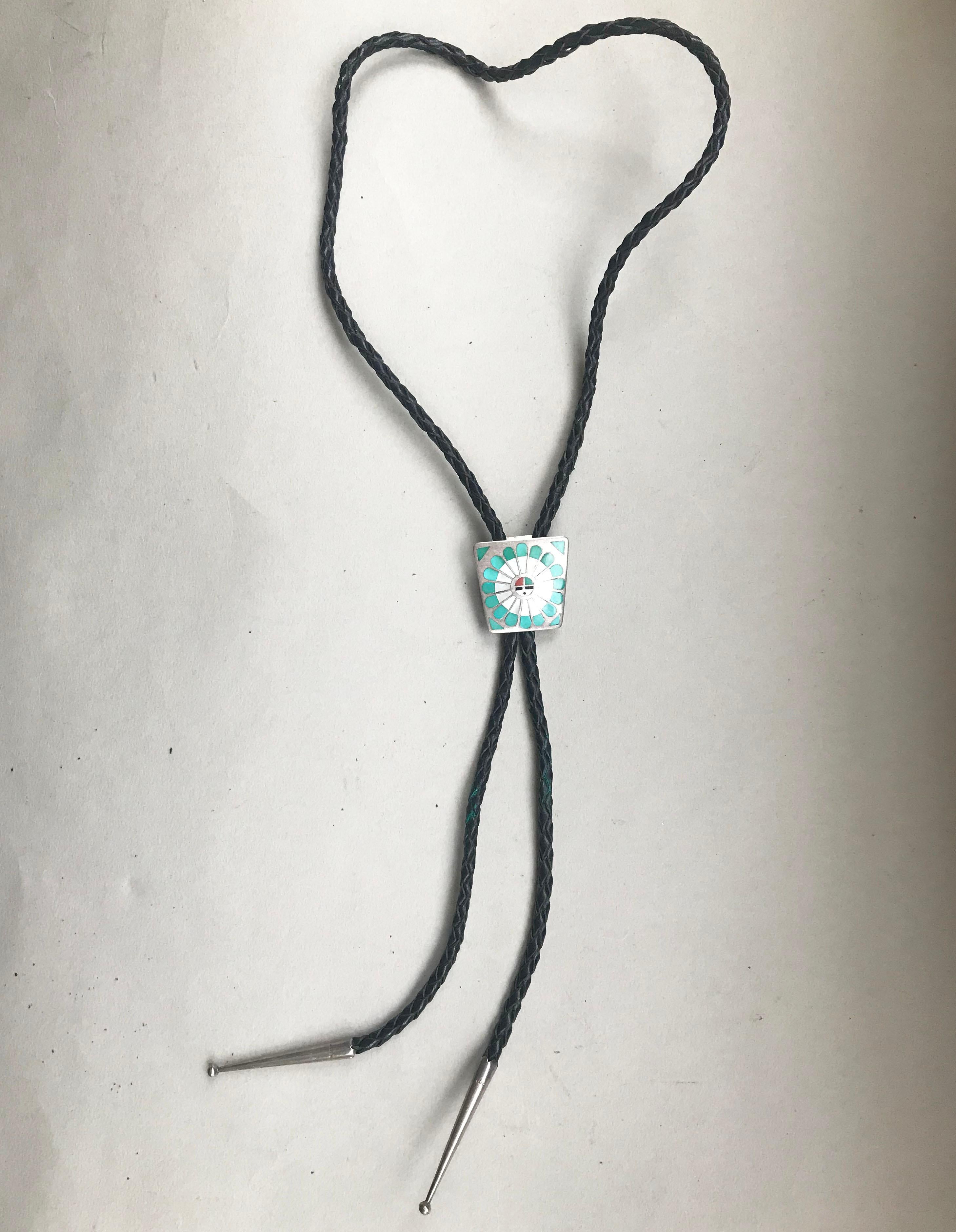 A handsome hand-crafted Sun design Zuni Bolo tie in sterling silver with natural stone inlay 
Circa 1960s.
With plaited black leather tie and sterling tips.

 
 
Measures: 1 1/2