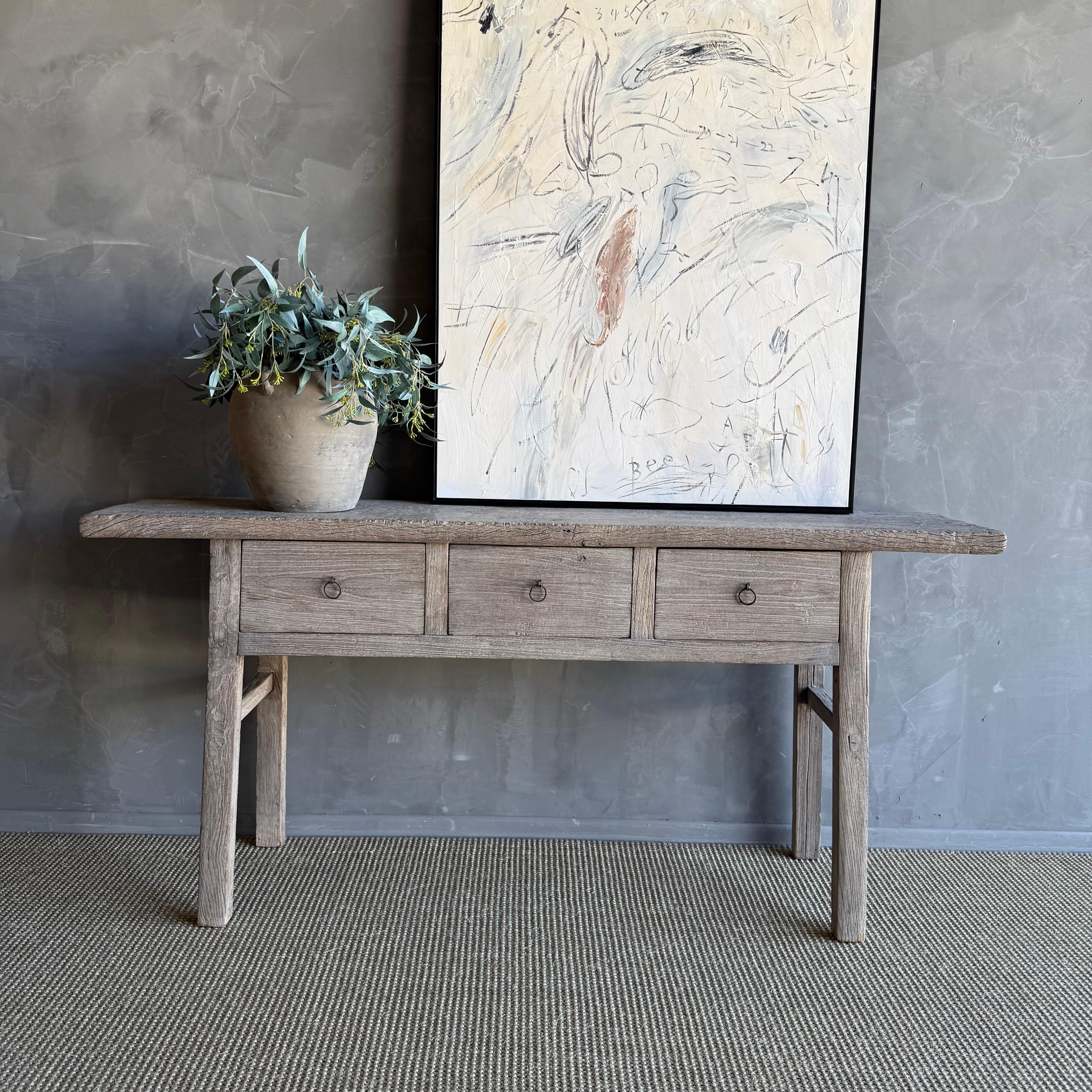 This charming vintage elm wood console is a one-of-a-kind piece with beautiful age and patina that adds character to any space. Its patina painted elm wood finish showcases the natural beauty of the wood, while the solid elm wood original hardware