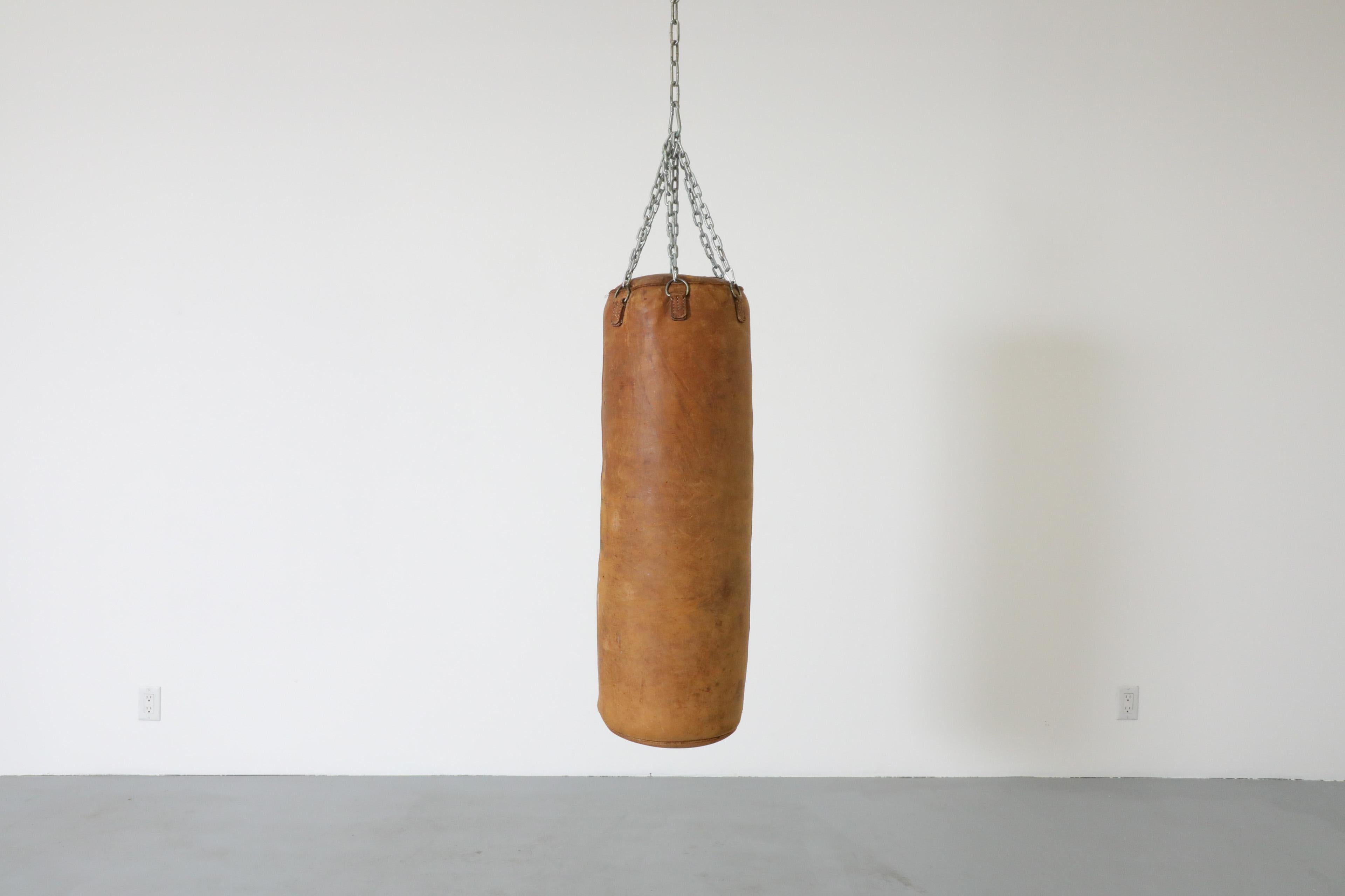 Vintage Boxsack mit schönem, abgenutztem Echtleder. Dieser hängende Boxsack ist eine stilvolle Ergänzung für ein Fitnessstudio zu Hause. Er wiegt ca. 30 lbs und ist im Originalzustand mit einigen sichtbaren Gebrauchsspuren. Dieses Stück ist eher ein