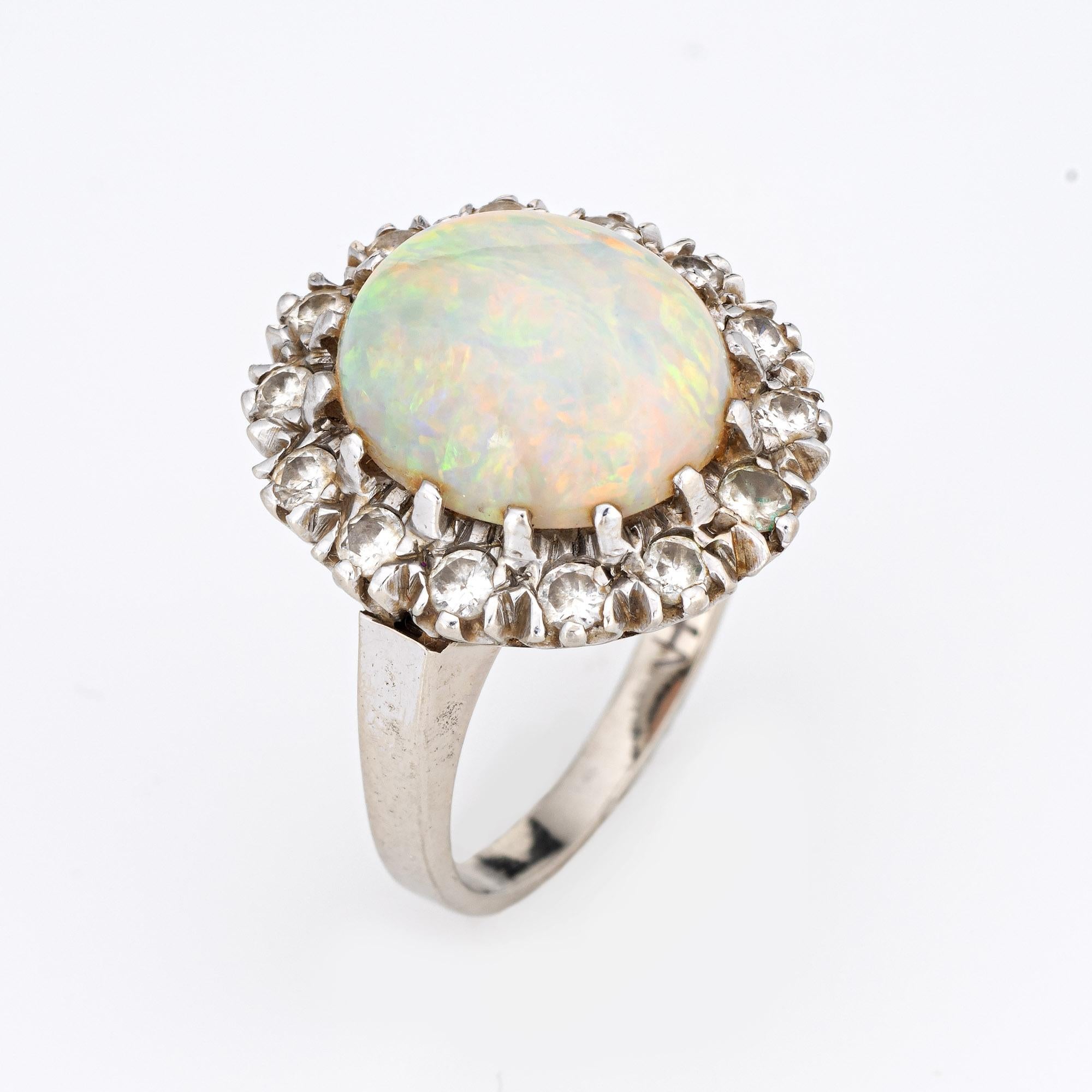 Finely detailed vintage opal & diamond cocktail ring (circa 1950s to 1960s), crafted in 14 karat white gold. 

Solid natural opal measures 12mm x 10mm (estimated at 5 carats) accented with 14 estimated 0.05 carat round brilliant cut diamonds. The