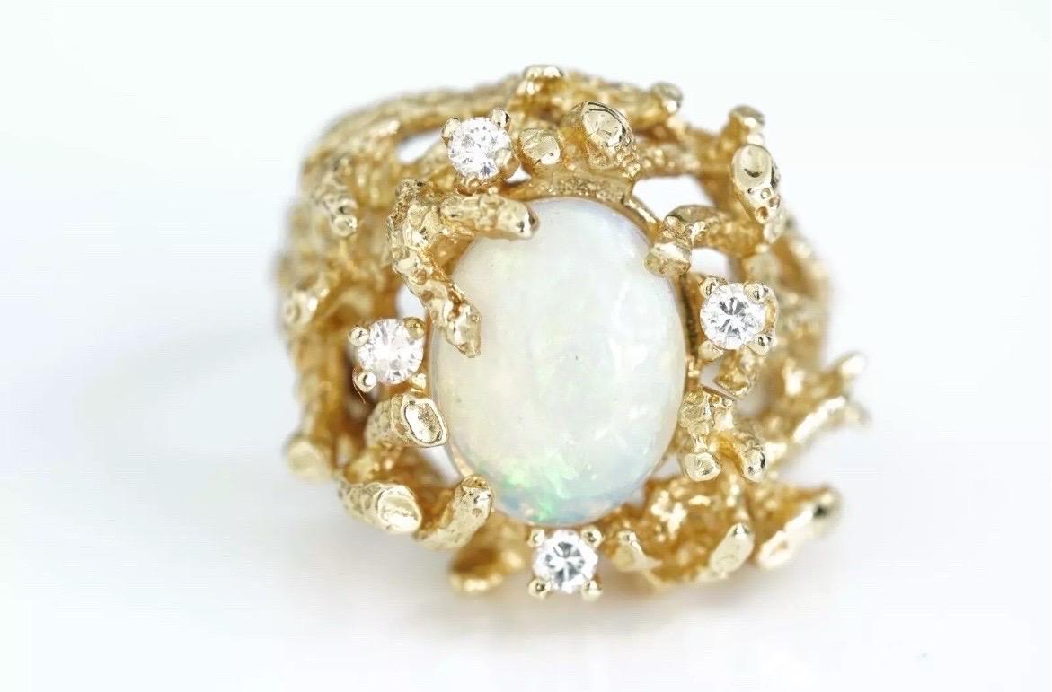 Fai colpo con questo sorprendente anello da cocktail Brutalista vintage, con al centro un'ipnotica opale naturale. Incastonato nell'oro giallo 14 carati, l'opale mostra un accattivante gioco di colori, con vivaci sfumature di verde, blu e arancione.