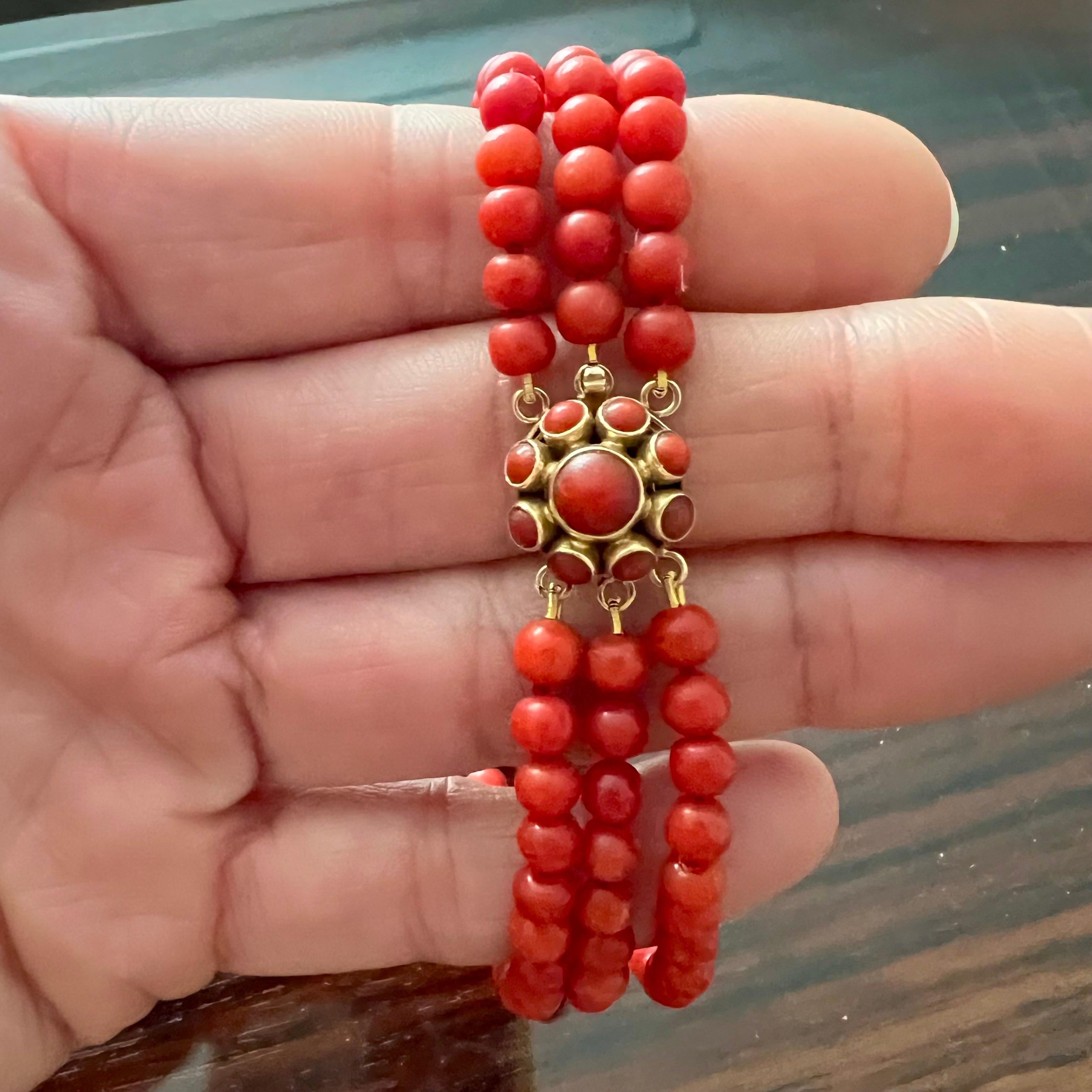 Dies ist ein dreireihiges Armband aus roter Koralle im Vintage-Stil mit einem Verschluss aus 14 Karat Gold. Die Korallenperlen sind rund und haben alle die gleiche Größe und Form. Die  Der schöne runde Verschluss ist mit einem Cluster aus roten