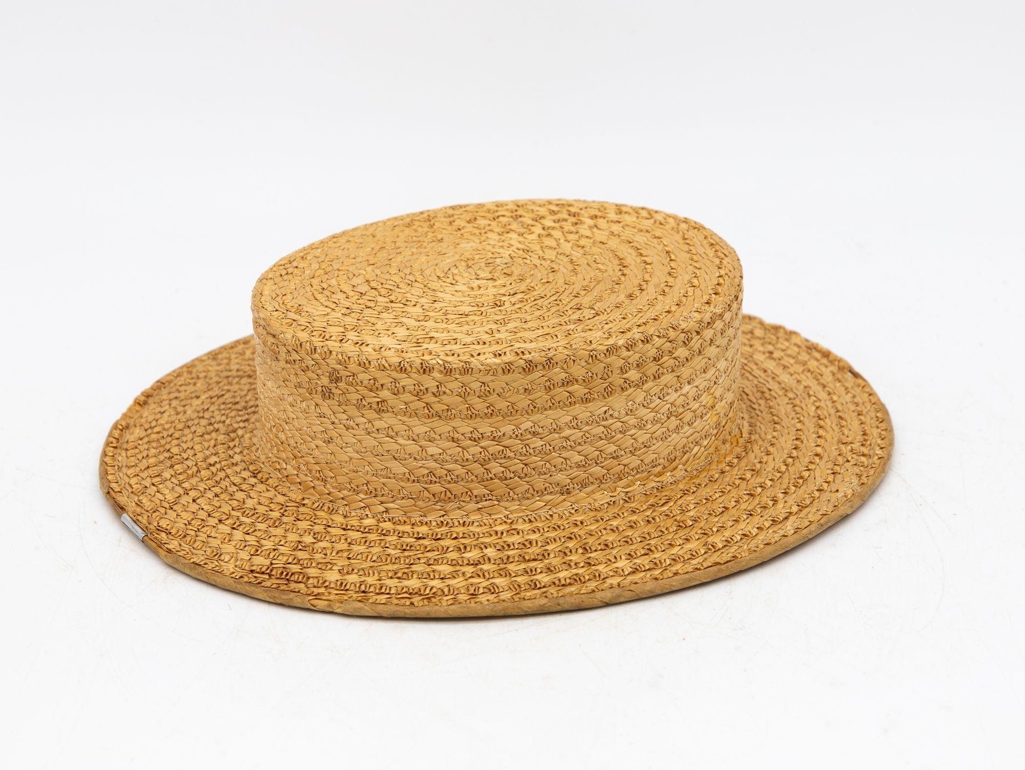 The Ridgemont Make's vintage 1950s boater hat showcases timeless elegance with its natural straw construction. Although the ribbon and bow are lost, this hat epitomizes classic style. This boater hat captures the essence of vintage summer fashion,