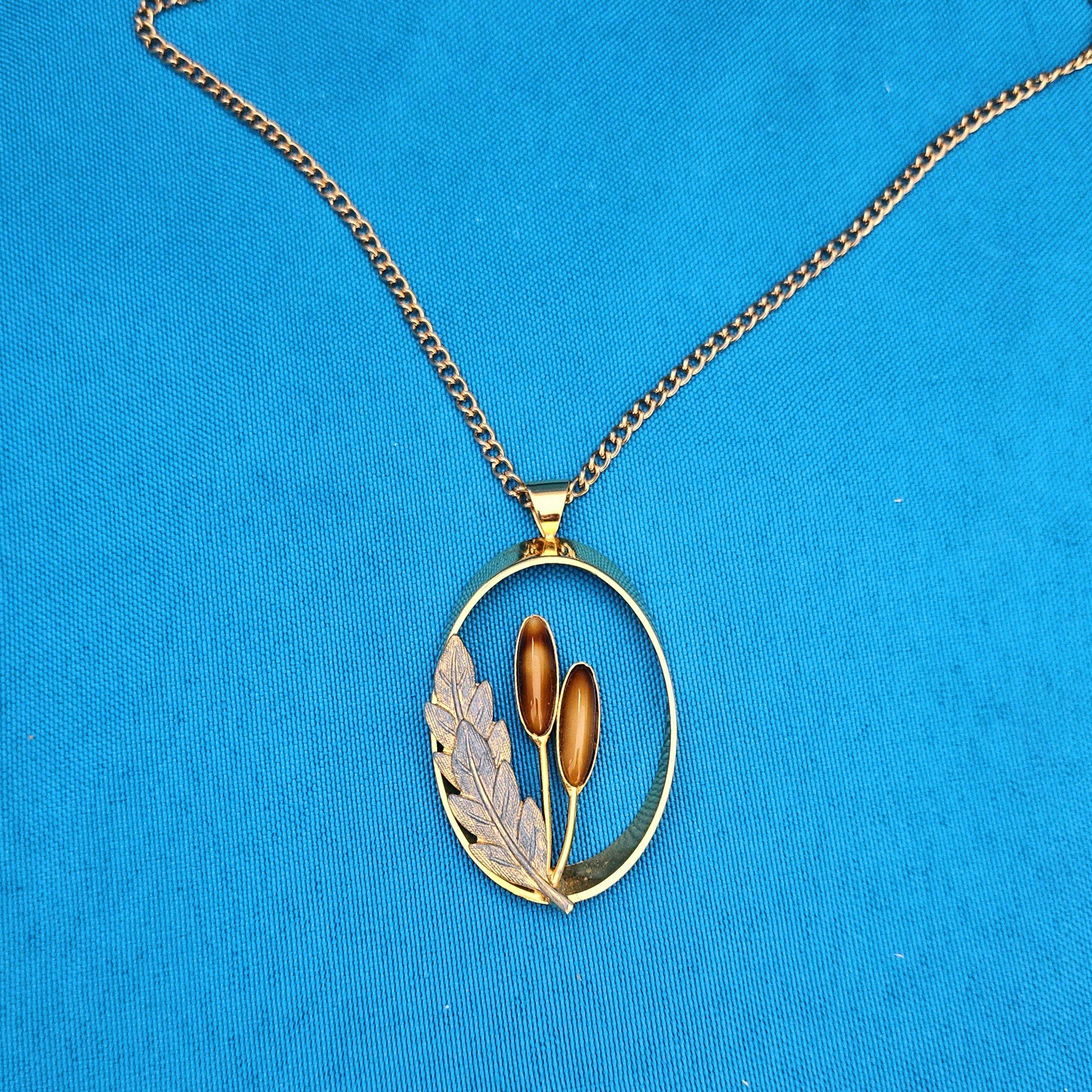 Collana vintage a tema Nature, ciondolo ovale aperto su catena lunga. 
Un bel pezzo per gli amanti della natura, questo ciondolo insolito con due pietre oblunghe, probabilmente finte, e un medaglione di fogliame applicato. È in ottime condizioni