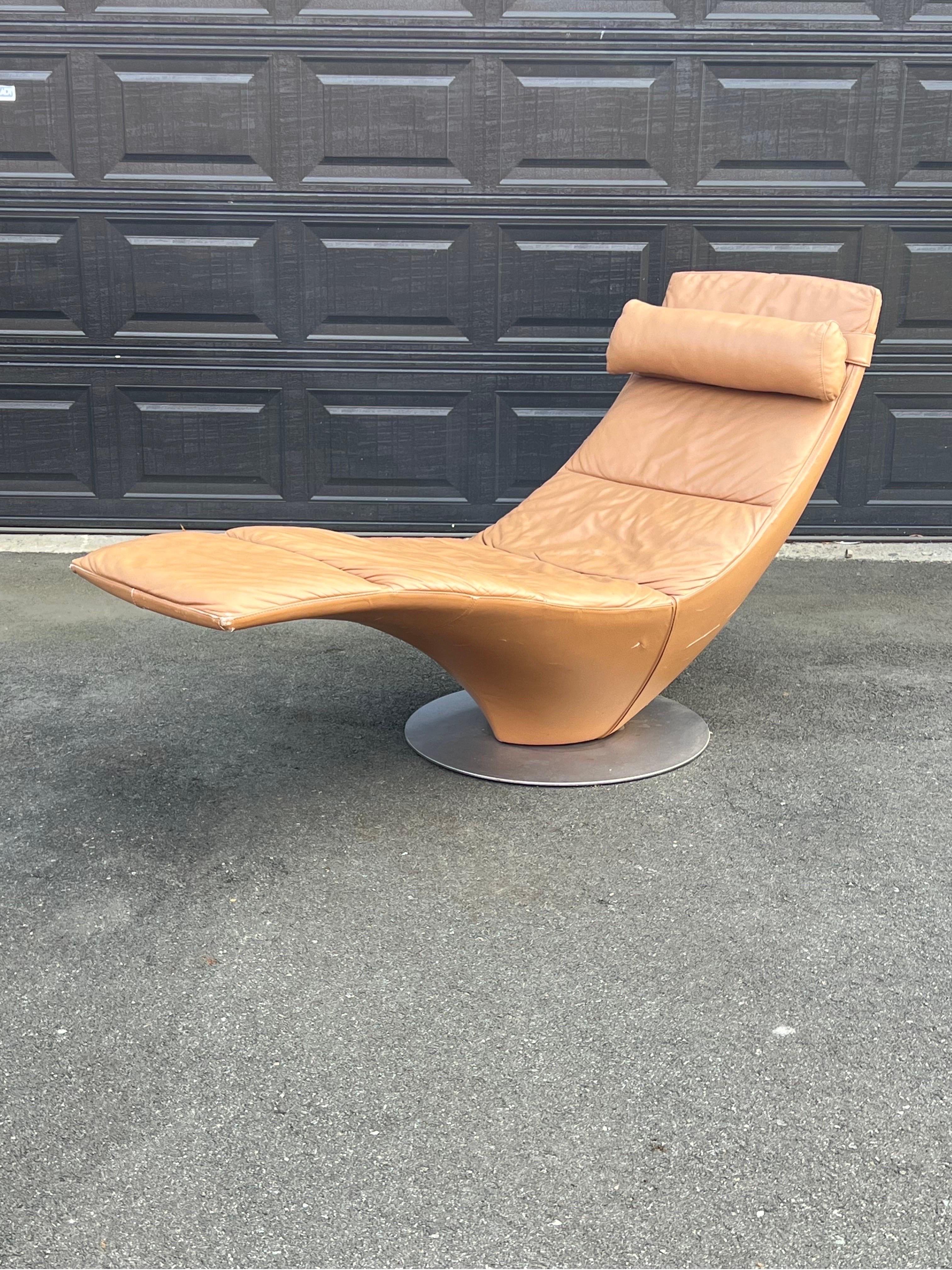 Modern chaise lounge designed by Natuzzi, Italy circa 1990s. This sculptural style chaise rests on a round metal base and swivels with ease. Extremely comfortable seating with original tan leather. Chaise is equipped with detachable head pillow with