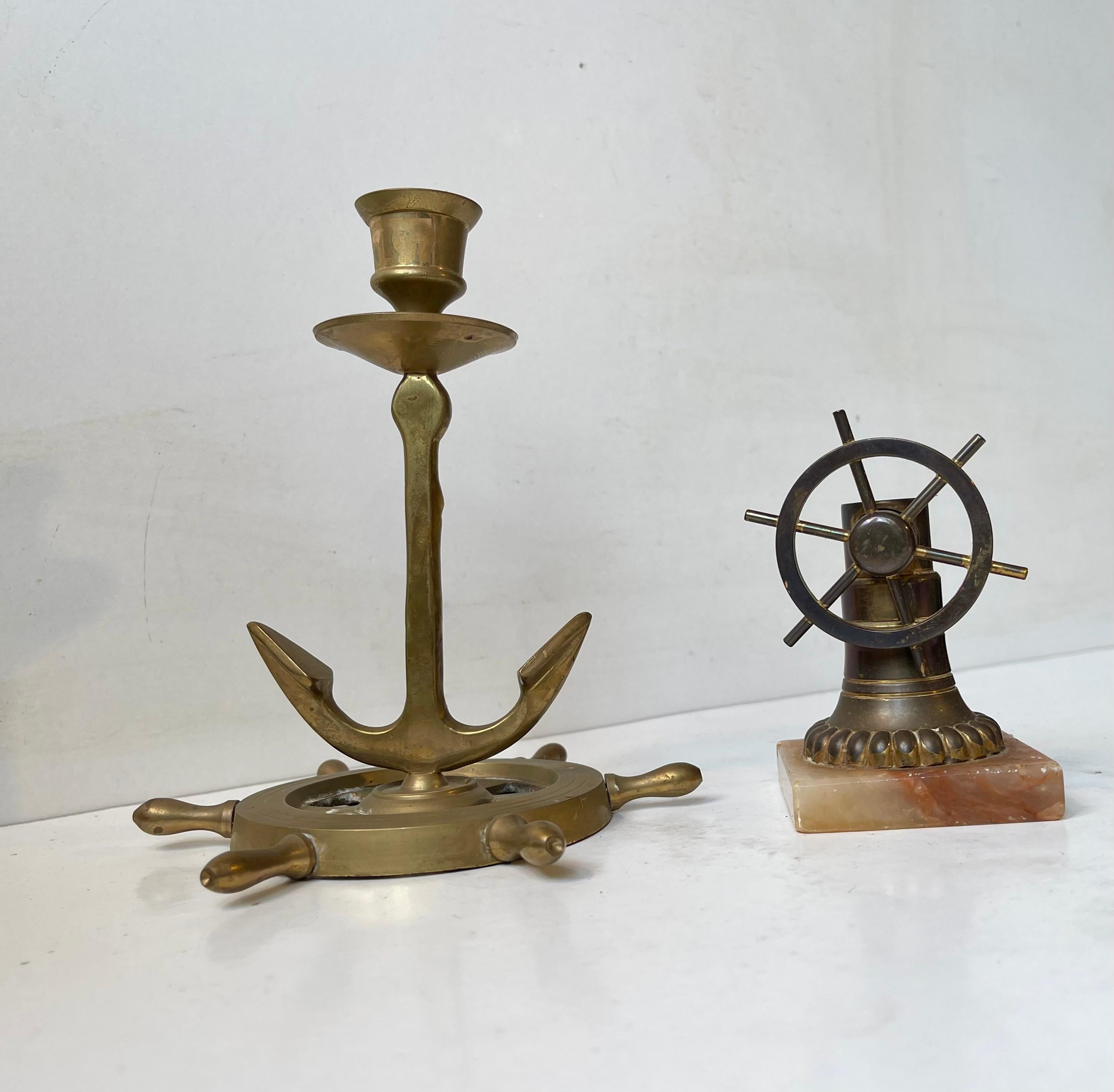 Nautical themed lot consisting of marble-based brass cigar cutter with a boats wheel cutting mechanism. It accompanied by a candleholder in the shape of an anchor with helm base. The set was made in Scandinavian during the 1930s or 40s.