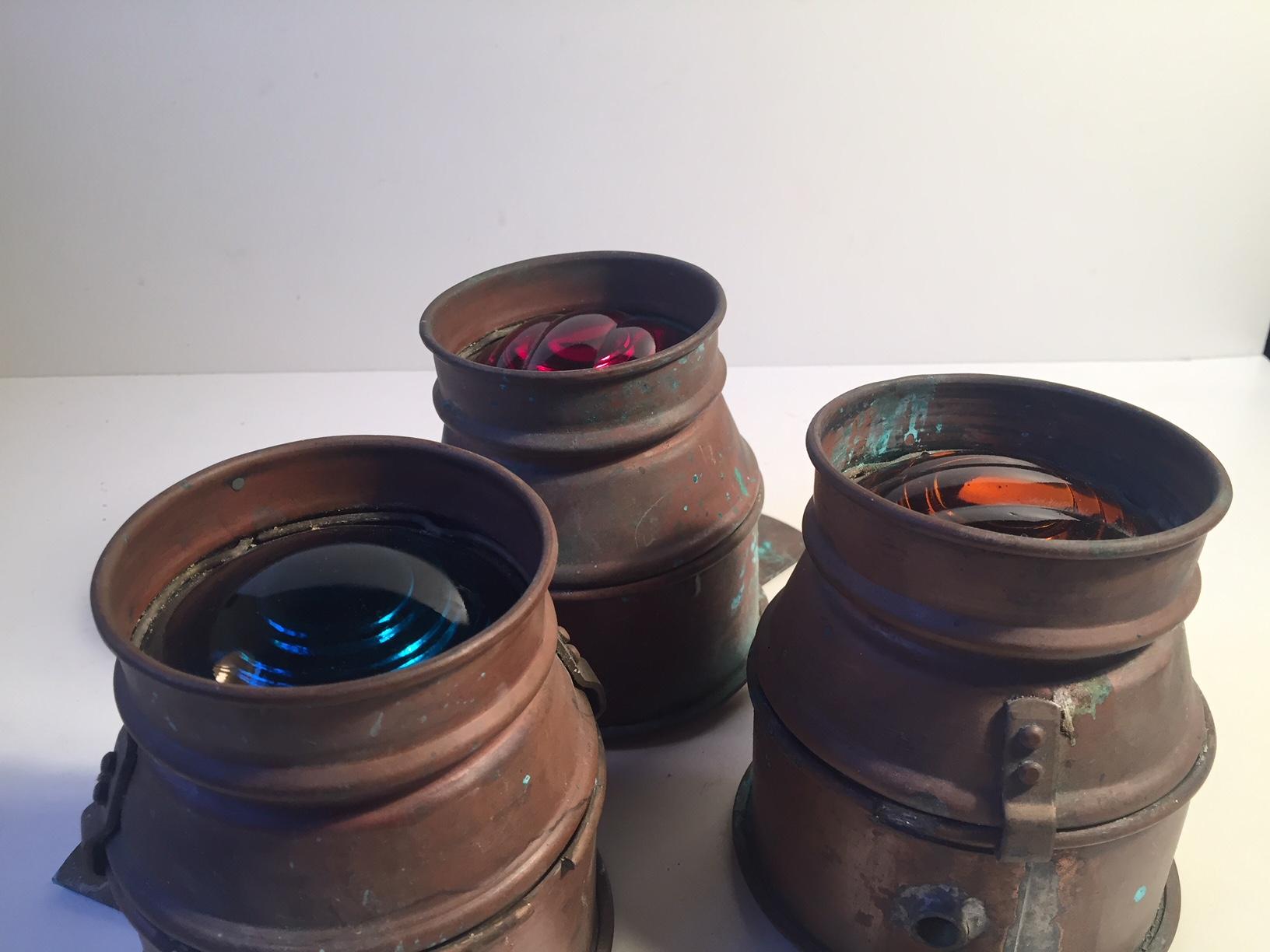 A trio of French maritime copper sconces with colored glass: orange, red and blue. They have been mounted on a ship as signal lights. They are all intact and installed with their original Bayonet Mount/socket typical of French lightning. The lights