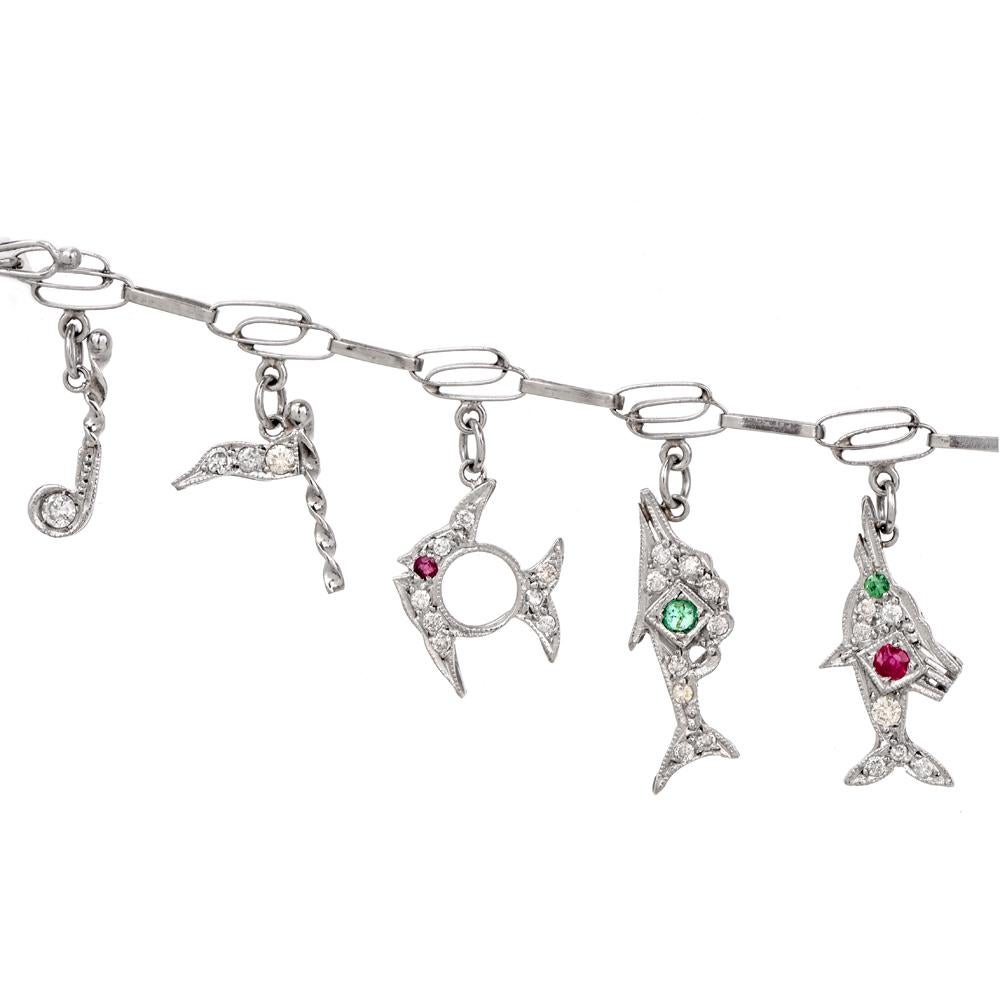 This nautical themed diamond, sapphire, emerald and ruby charm vintage bracelet is crafted in solid platinum. Composed of interlocking double oval shaped links. The bracelet is enriched with ten charms including a pave diamond and sapphire sail