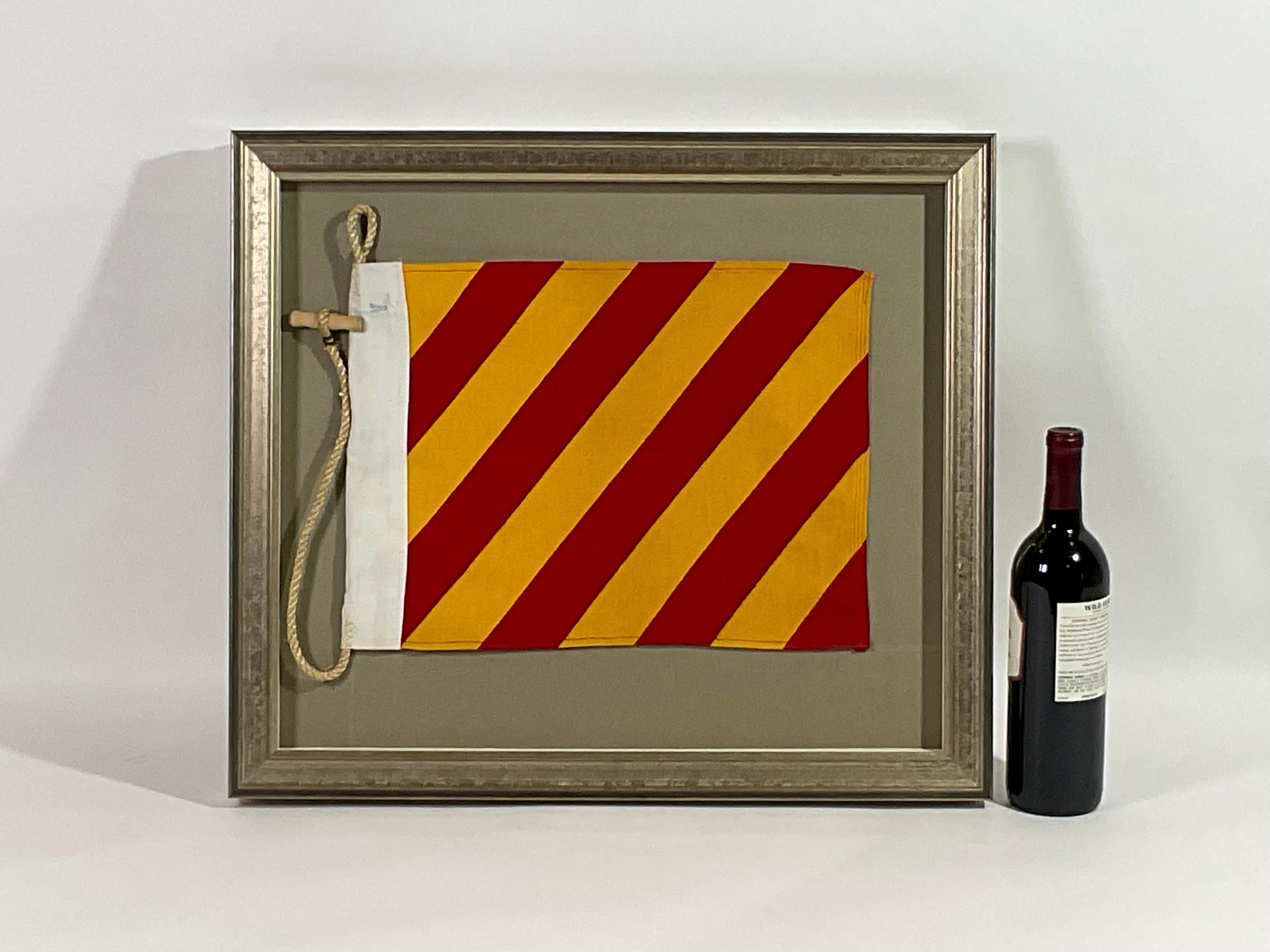 Framed maritime signal flag representing the letter “Y” code name YANKEE in the international code of signals. This authentic pennant red and yellow cotton is fitted to a heavy canvas hoist band with original rope and toggle. This nautical relic is