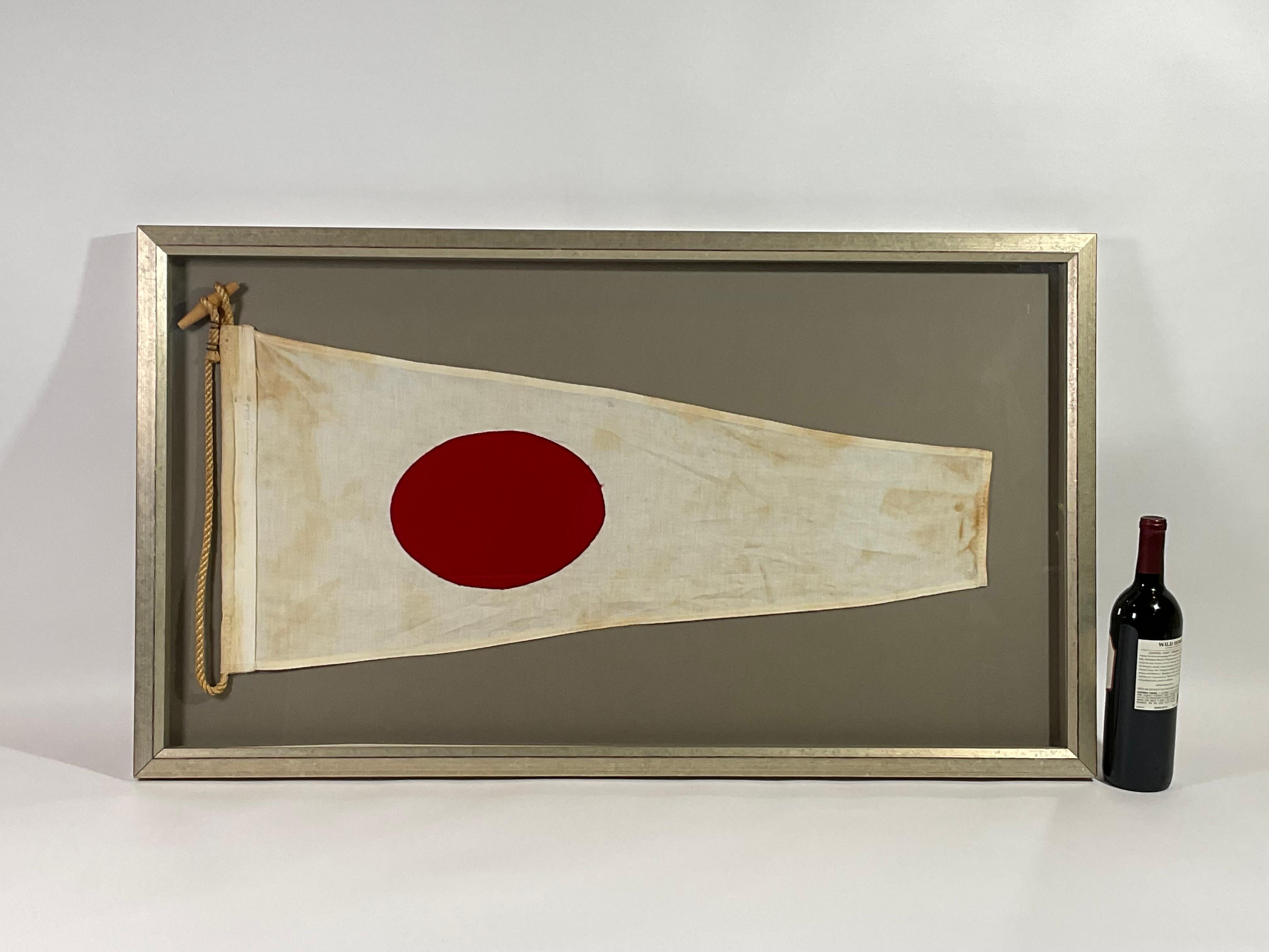 Framed maritime signal flag representing the number “3”, “THREE” in the international code of signals. This authentic and ocean used pennant is made of individual panels of red, white and blue. Fitted to a heavy canvas hoist band with original rope