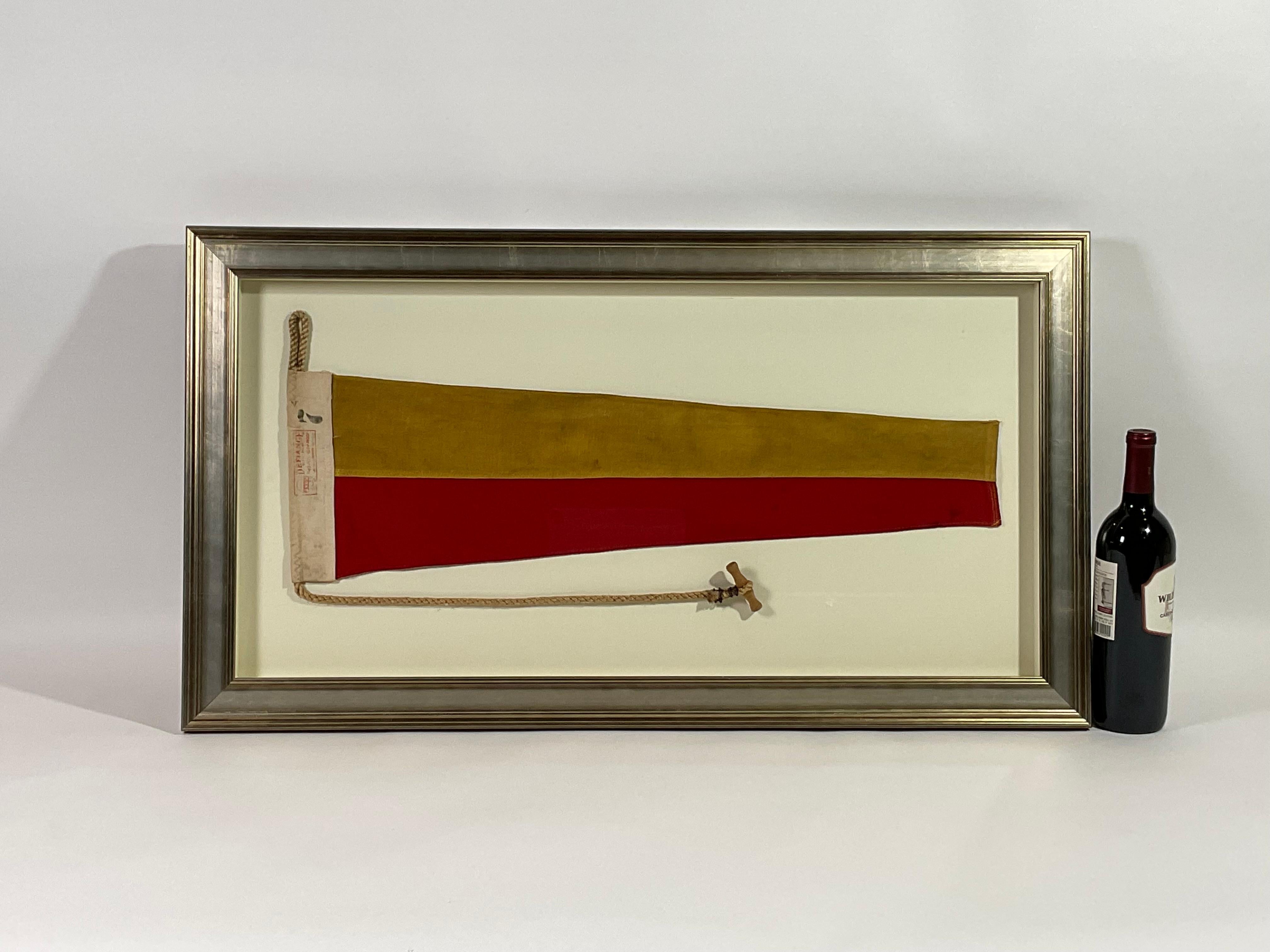 Framed maritime signal flag representing the number “7”, “SEVEN” in the international code of signals. This authentic and ocean used pennant is made of individual panels of red and yellow. Fitted to a heavy canvas hoist band with original rope and