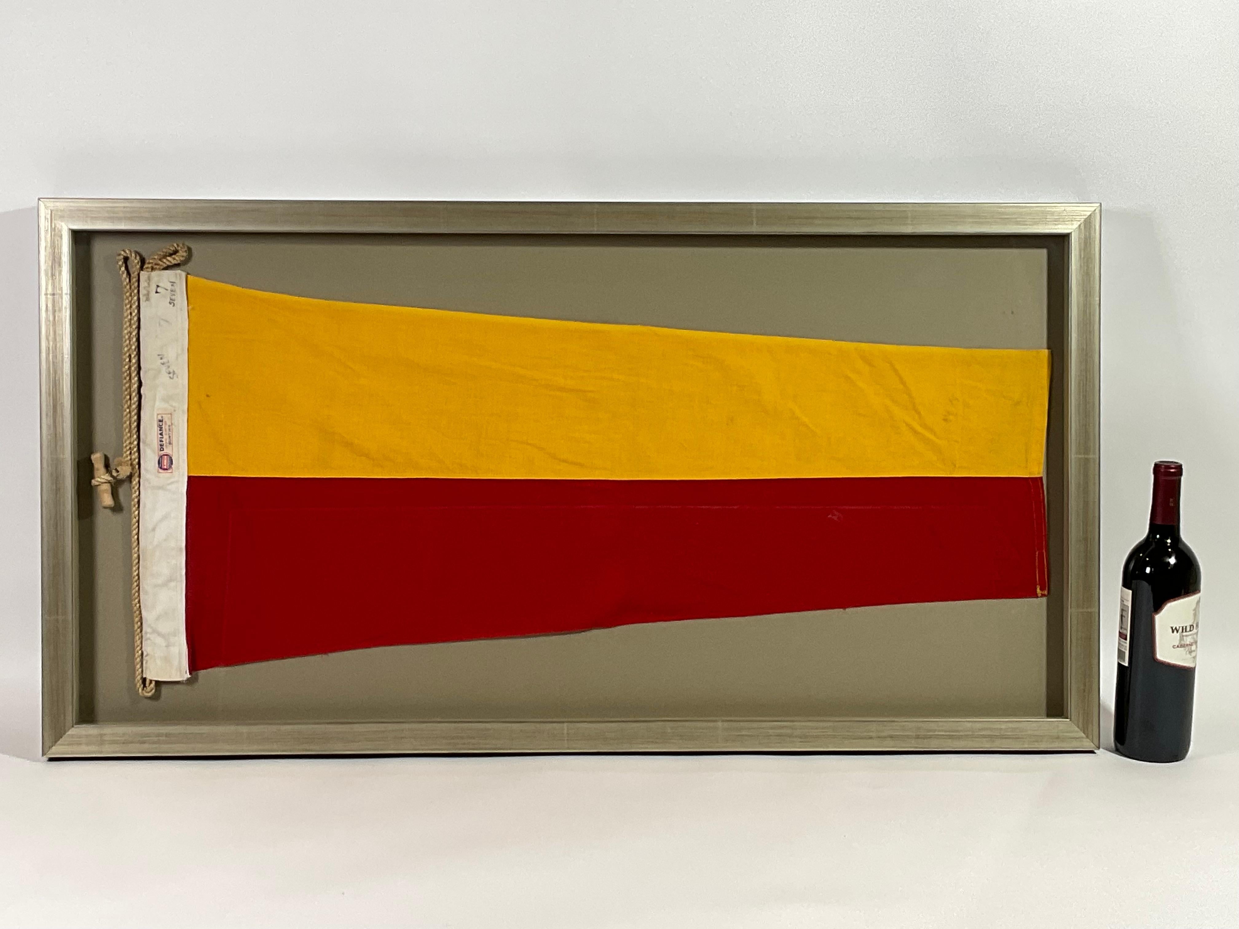 Framed maritime signal flag representing the number “7”, “SEVEN” in the international code of signals. This authentic and ocean used pennant is made of individual panels of yellow and red. Fitted to a heavy canvas hoist band with original rope and