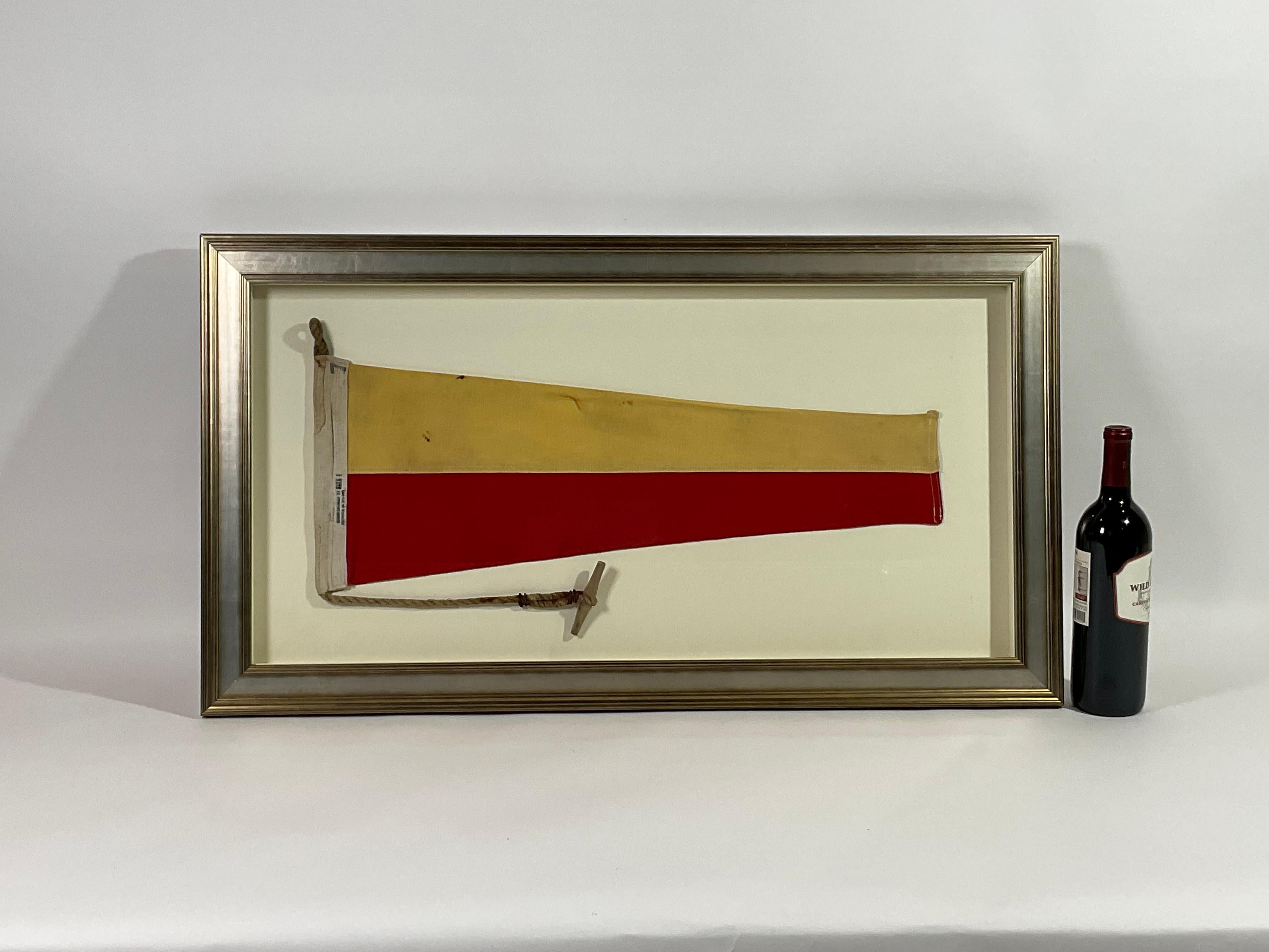 Framed maritime signal flag representing the number “7”, “SEVEN” in the international code of signals. This authentic and ocean used pennant is made of individual panels of yellow and red. Fitted to a heavy canvas hoist band with original rope and