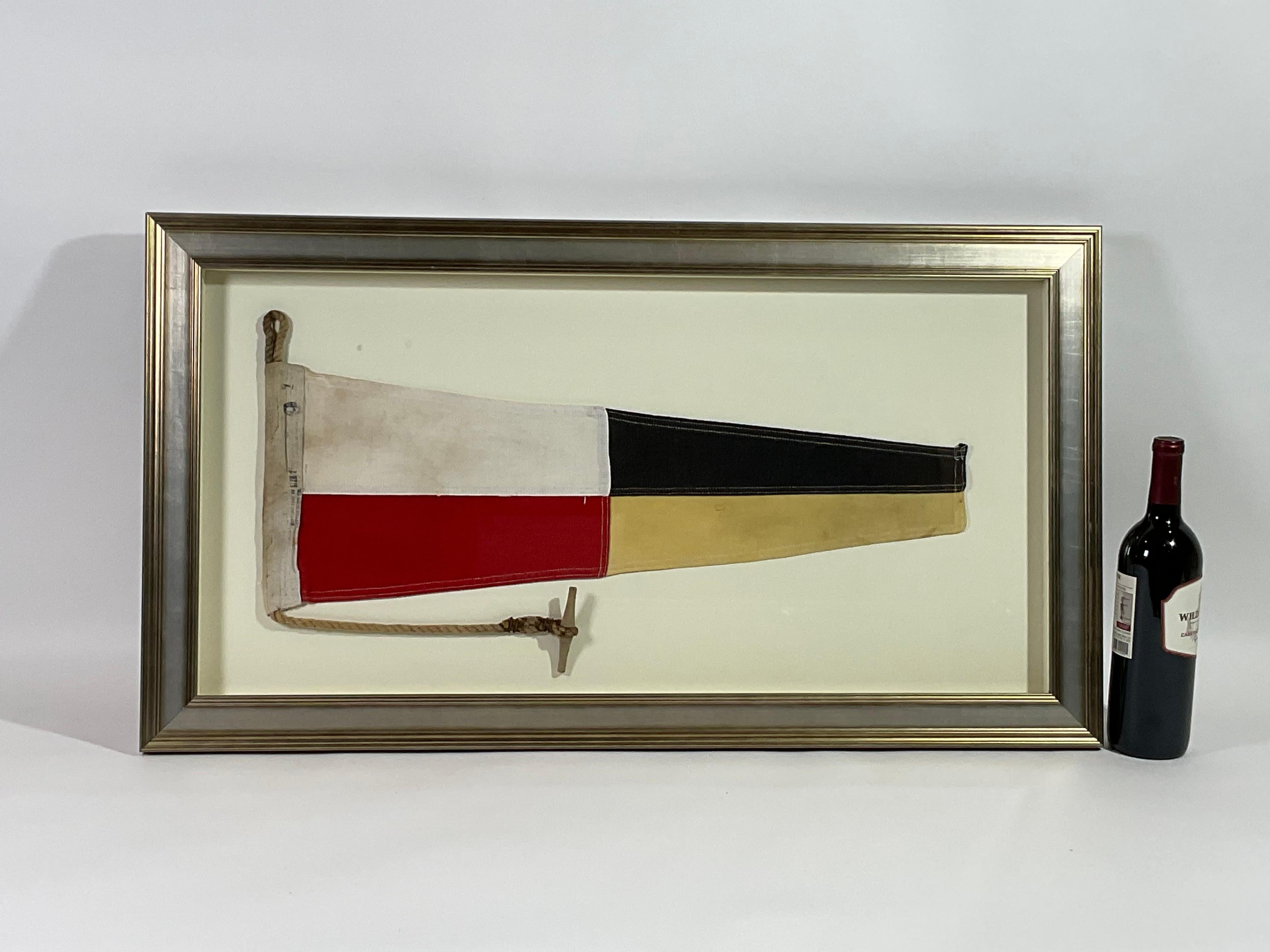Framed maritime signal flag representing the number “7”, “SEVEN” in the international code of signals. This authentic and ocean used pennant is made of individual panels of yellow and red. Fitted to a heavy canvas hoist band with original rope and