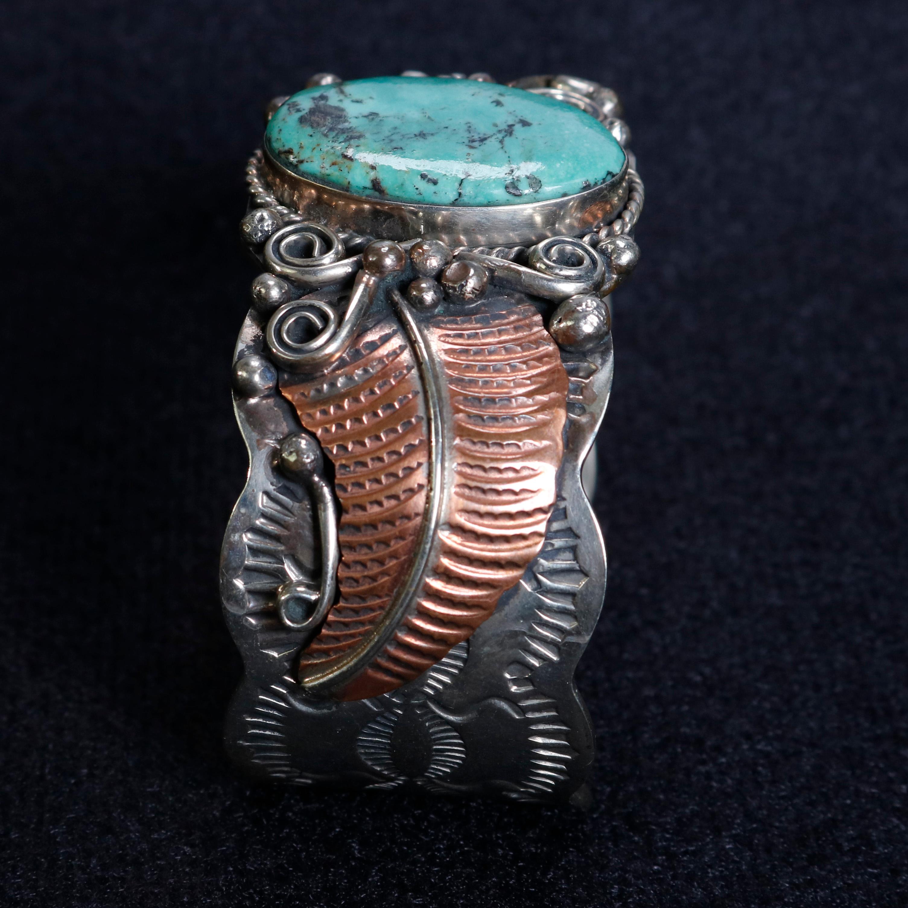 A vintage native American Navajo Indian handcrafted cuff bracelet by Albert Cleveland offers shaped sterling silver band having central turquoise seated in beveled setting and flanked by copper leaves and scroll decoration, maker mark as