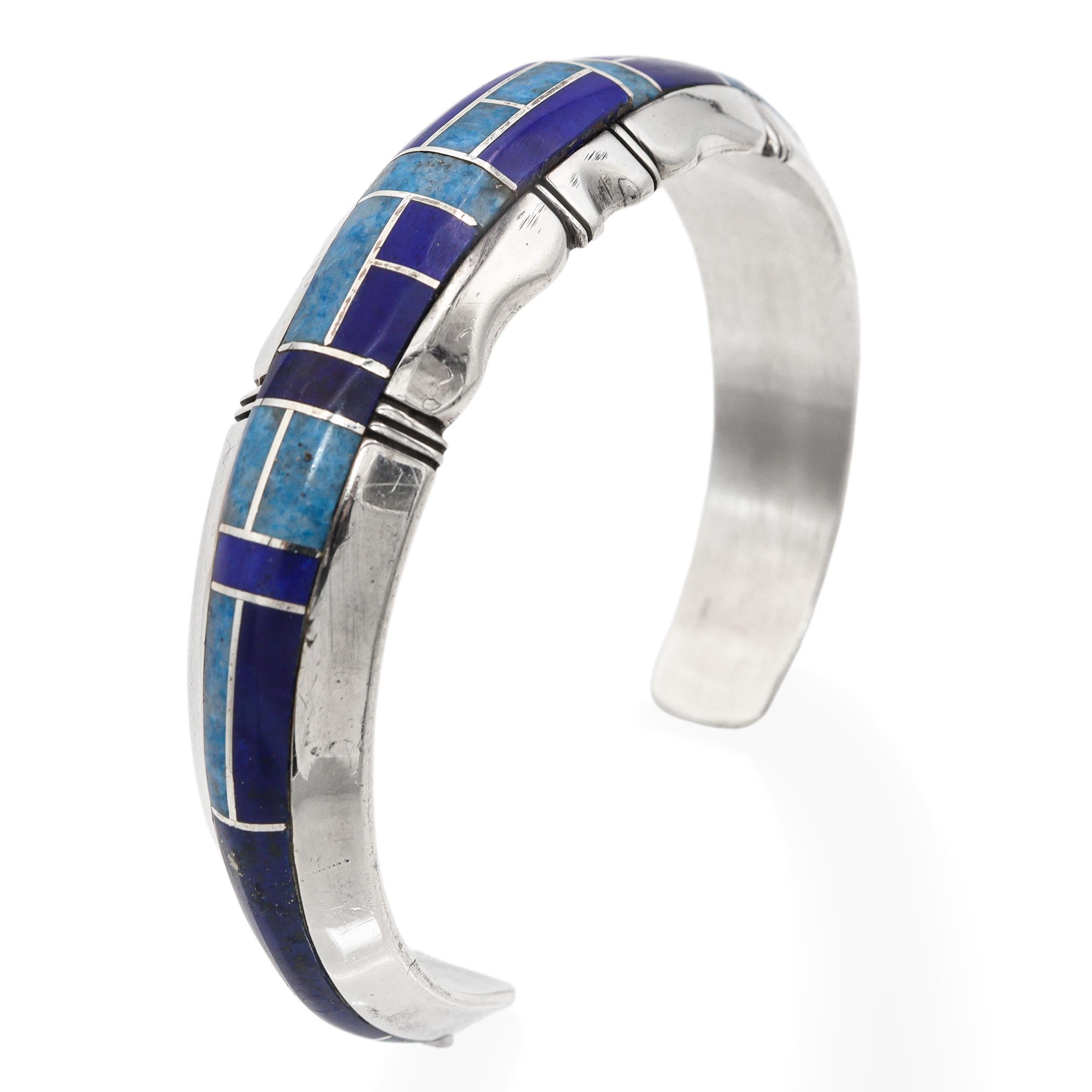Ce bracelet manchette vintage exceptionnel est l'œuvre de l'orfèvre Navajo Gilbert Nelson, connu pour ses incrustations magistrales. Fabriqué en argent sterling, ce bracelet présente un motif d'incrustation pierre à pierre saisissant composé de