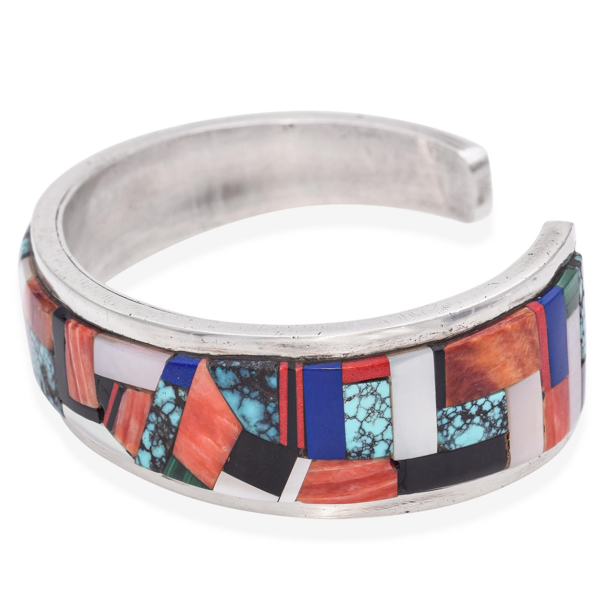 Realizzato in argento sterling, questo bracciale presenta un vivace intarsio di turchese, corallo, lapis, malachite, madreperla e onice. L'intricato disegno a mosaico crea una dichiarazione audace e colorata.

Lunghezza: 6,25
Peso: 39,8 g