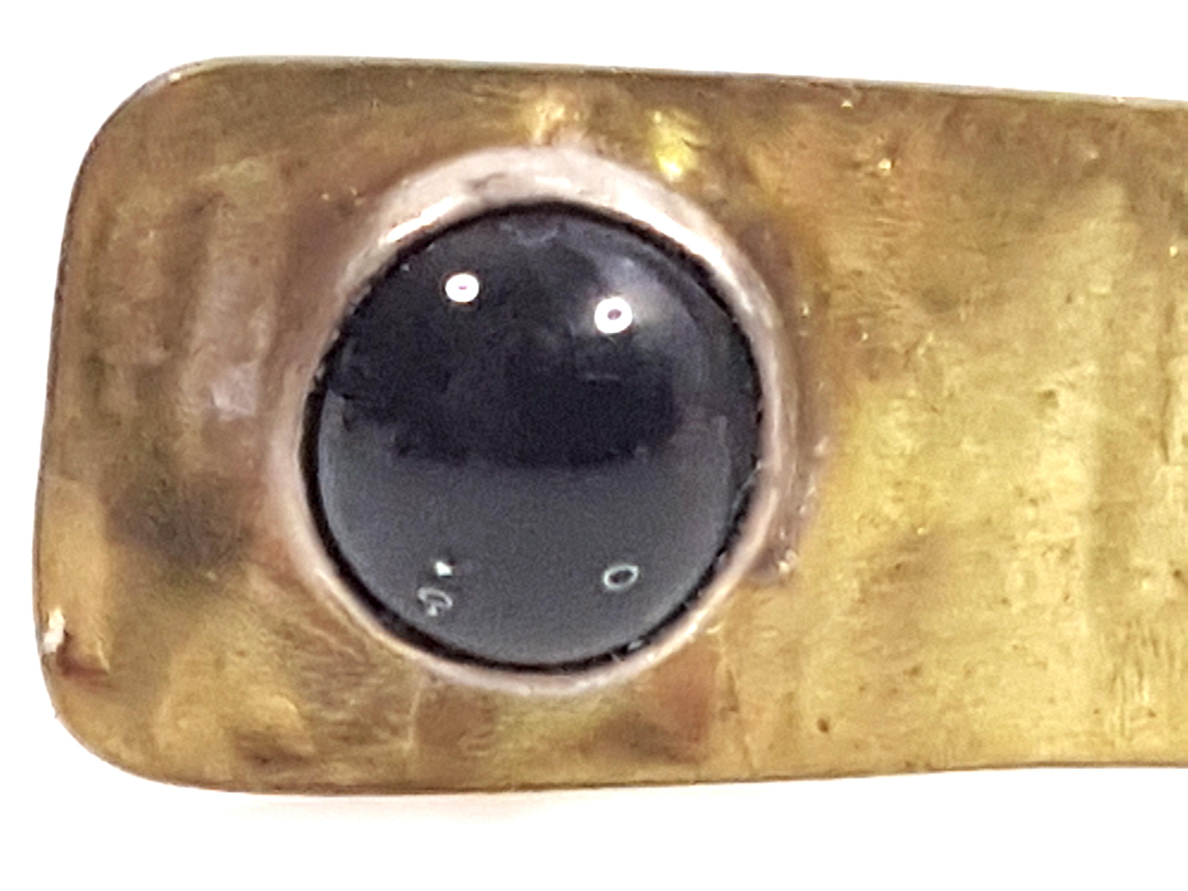 This vintage Navajo modern minimal statement solitaire ring that was handmade by an unknown Native American features a sterling-bezel set black onyx cabochon on one end of a linear-textured yellow gold-filled asymmetrical narrow top, which spans