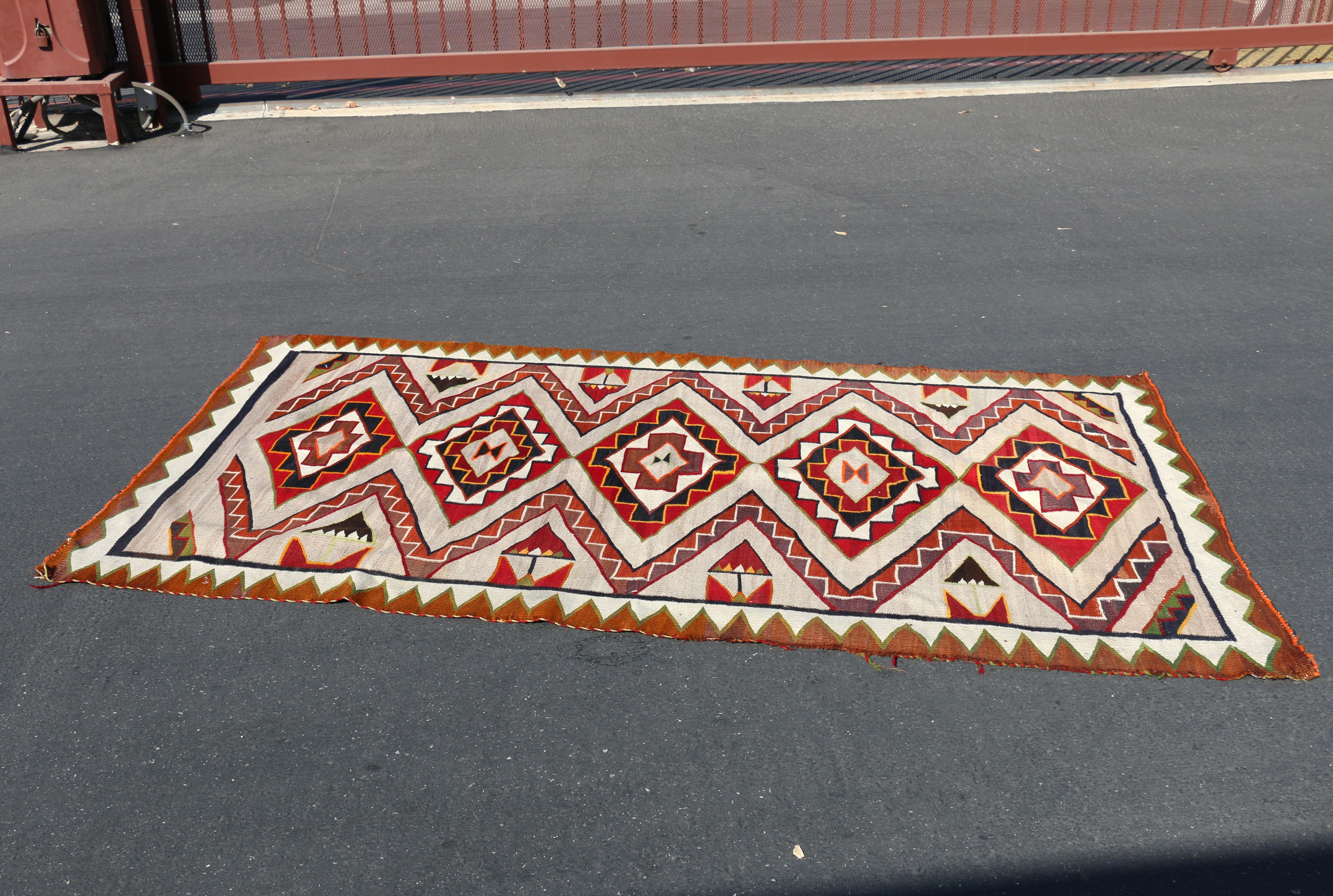 Spettacolare tappeto Navajo, caratterizzato da motivi geometrici distintivi e da colori ricchi, in particolare rosso, bianco, verde e arancione. Questo stile di tessitura è profondamente radicato nella storia e nella cultura del popolo Navajo