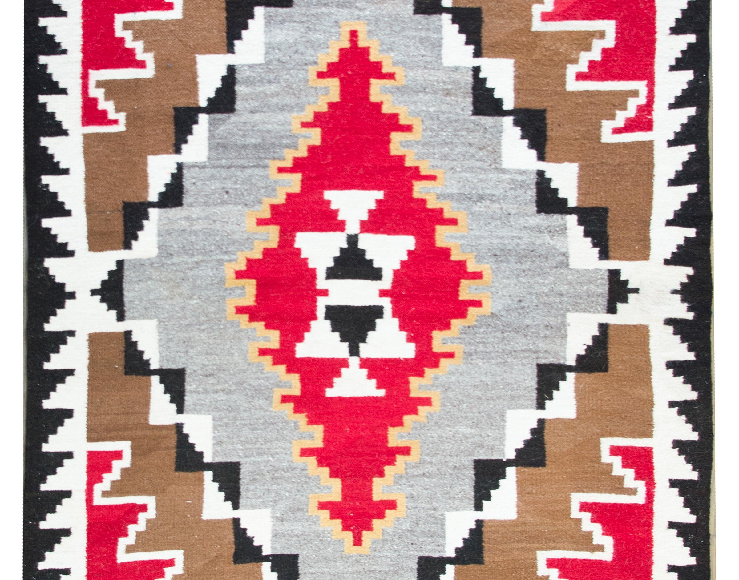 A stunning vintage Navajo rug with a pattern of diamonds reducing size and changing in color, and separated by zigzag or triangle patterns, all woven in crimson, brown, gold, black and white wool.