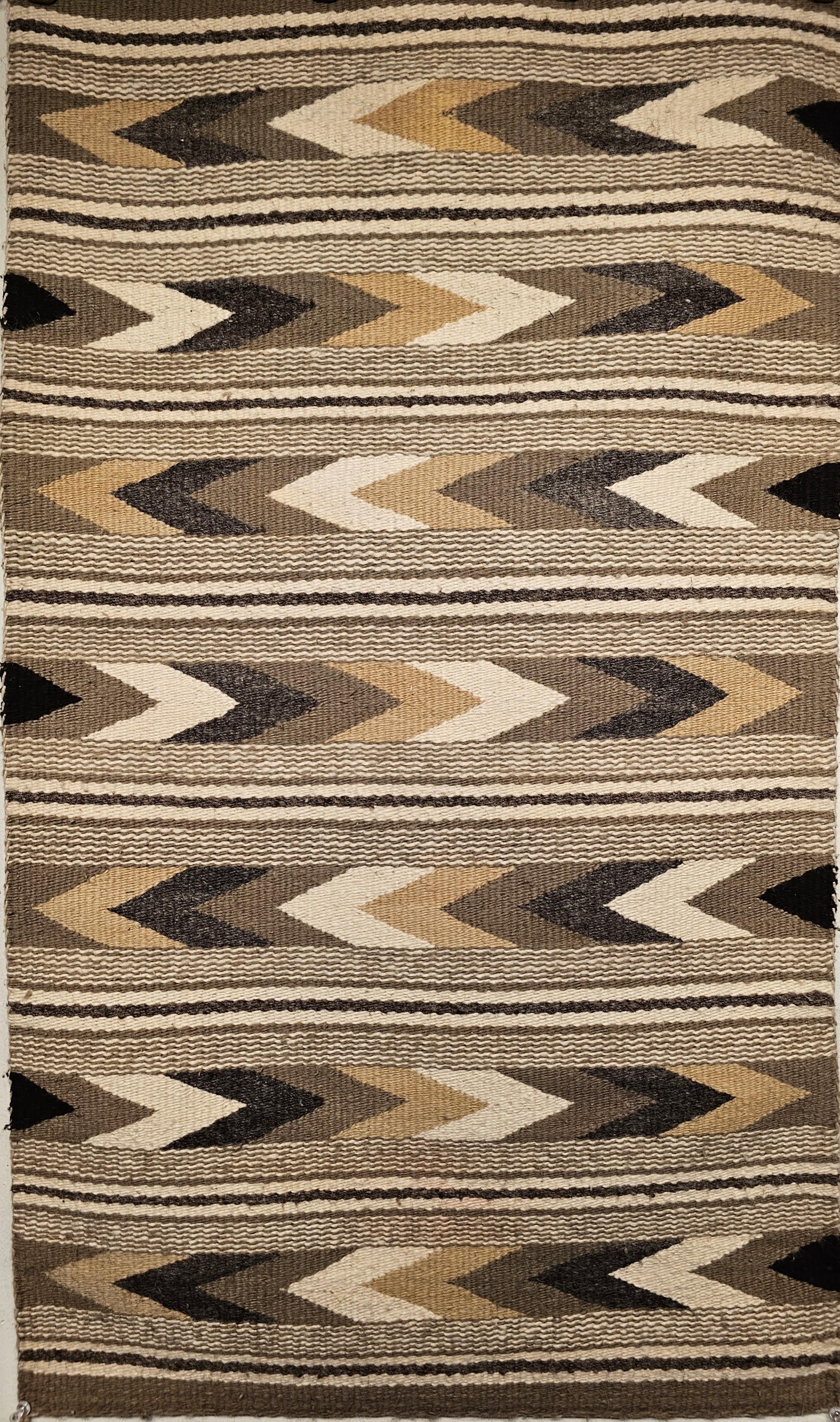  Vintage American Navajo rug in a banded chevron and stripe pattern with natural earth tone colors including gray, ivory, black, and caramel from the 3rd quarter of the 1900s.    Navajo weavers use natural organic dyes that are available around