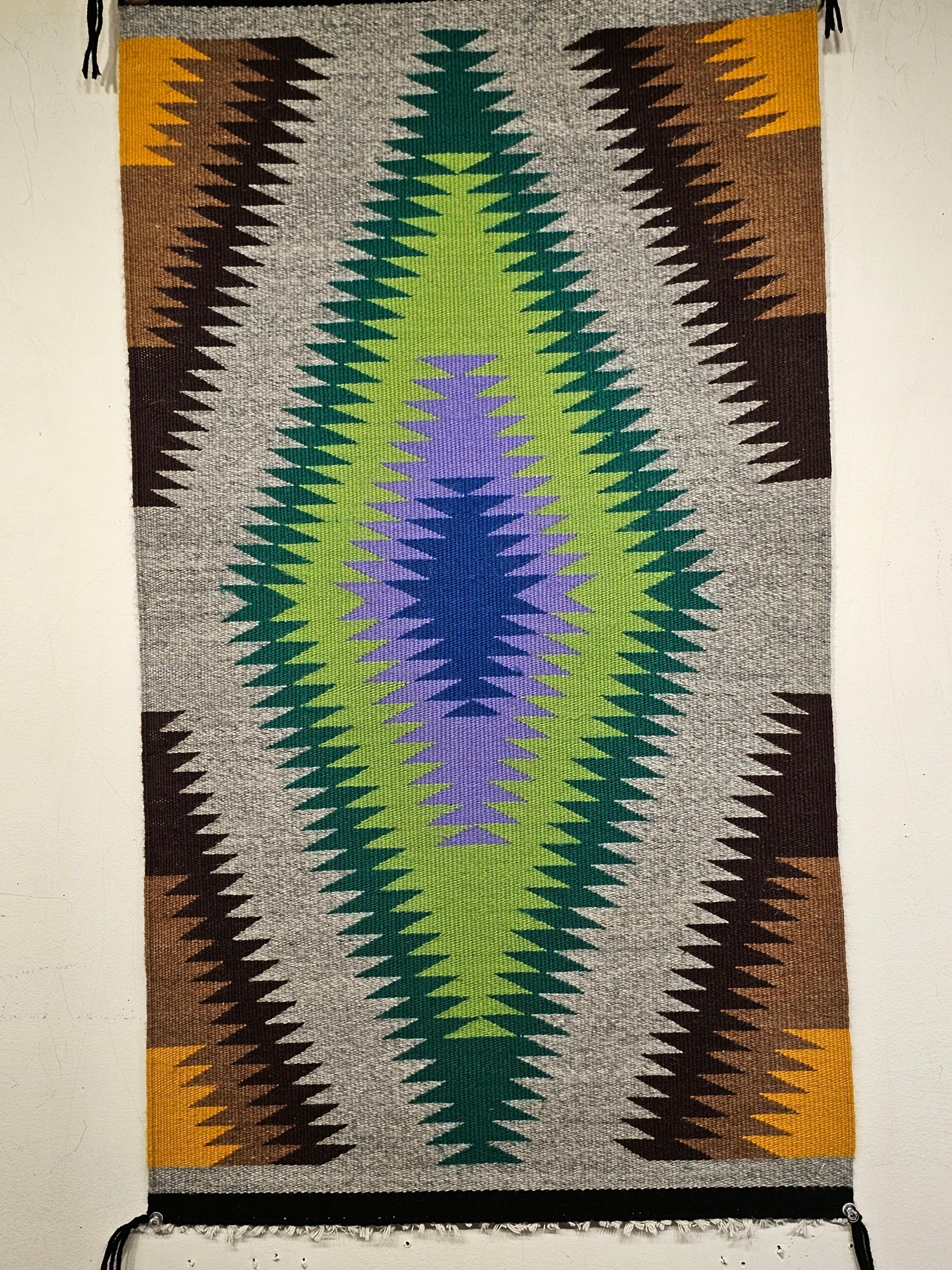 Beautiful vintage Navajo weaving from the SW United States from the mid 1900s. This Navajo rug has a series of diamond form designs radiating out from the center changing color like the color spectrum.  Each diamond consists of a different color