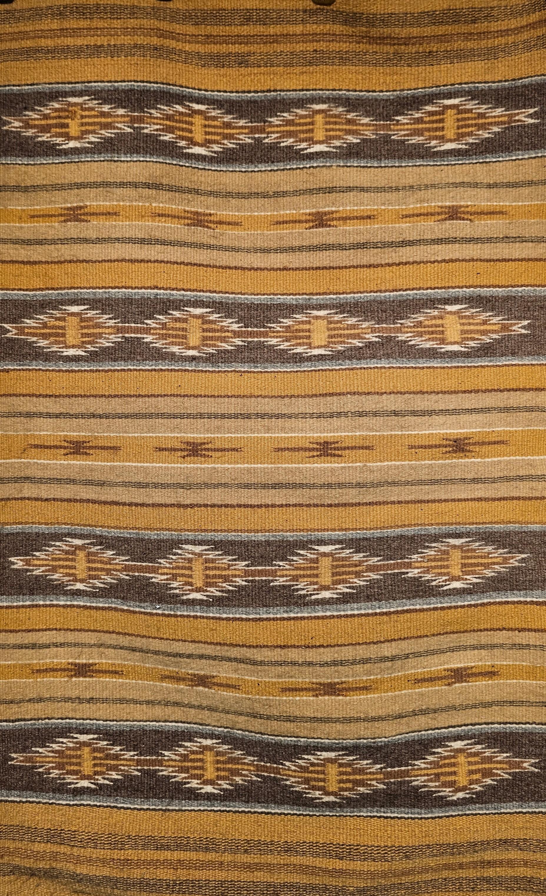 Vintage Navajo rug in a banded and stripe pattern with natural earth tones including gray, ivory, black, and caramel from the 3rd quarter of the 1900s.    The rug contains major bands with star geometric design set in a dark gray background