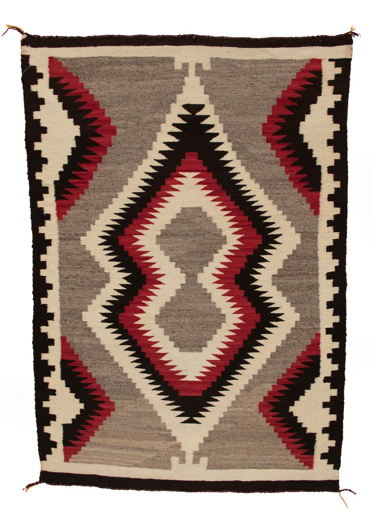 Vintage antique Navajo rug from the Trading Post era, circa 1900-1925. Woven by hand by a Navajo weaver of native hand-spun wool in natural fleece colors of ivory, gray and black brown with aniline dyed red. This textile is well suited for use on