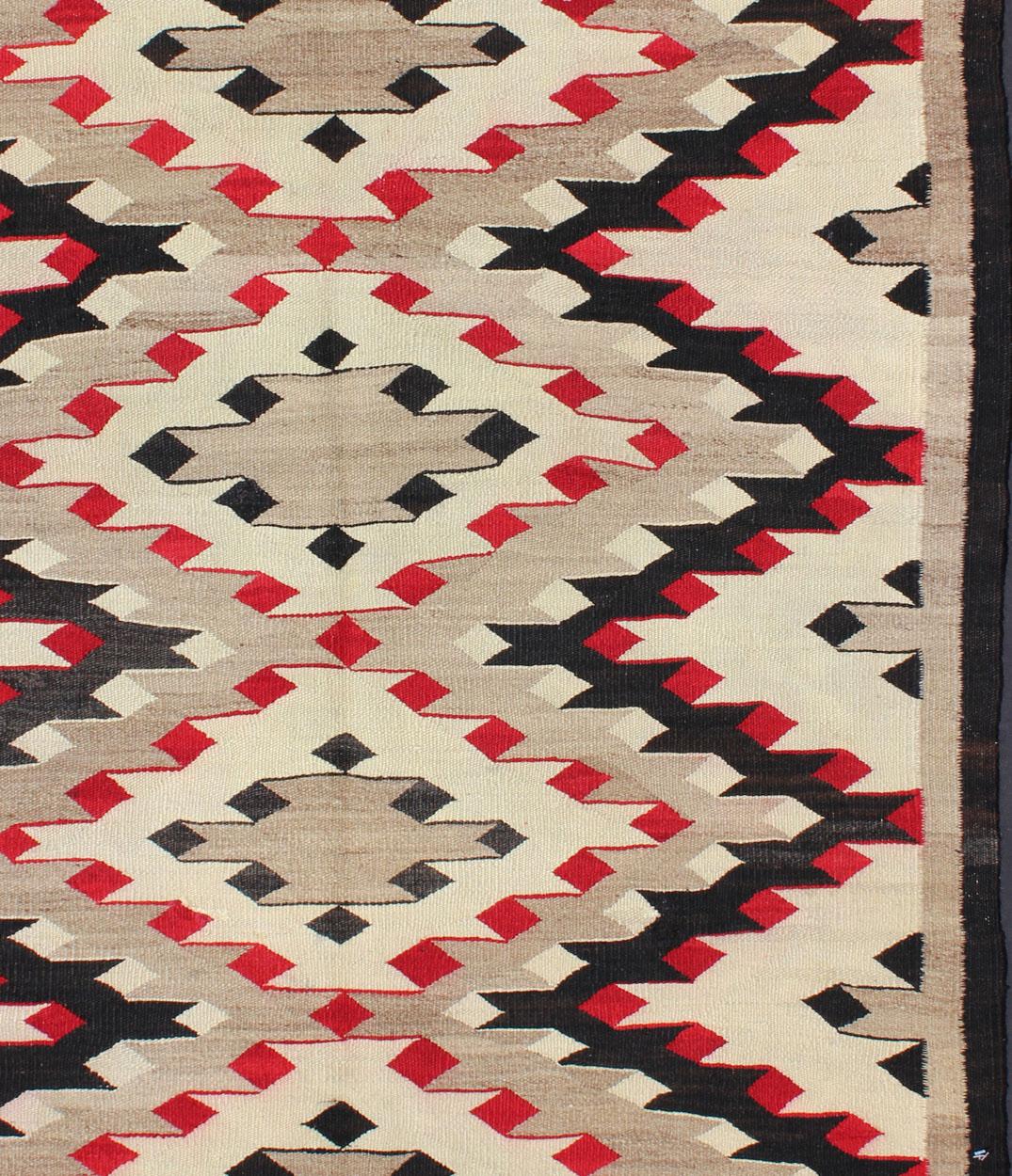 Cet intriguant tapis Navajo vintage a été tissé par les tribus Navajo durant la première moitié du 20e siècle. Cette composition unique et passionnante présente une composition géométrique captivante avec un motif de médaillon diamanté sur toute la