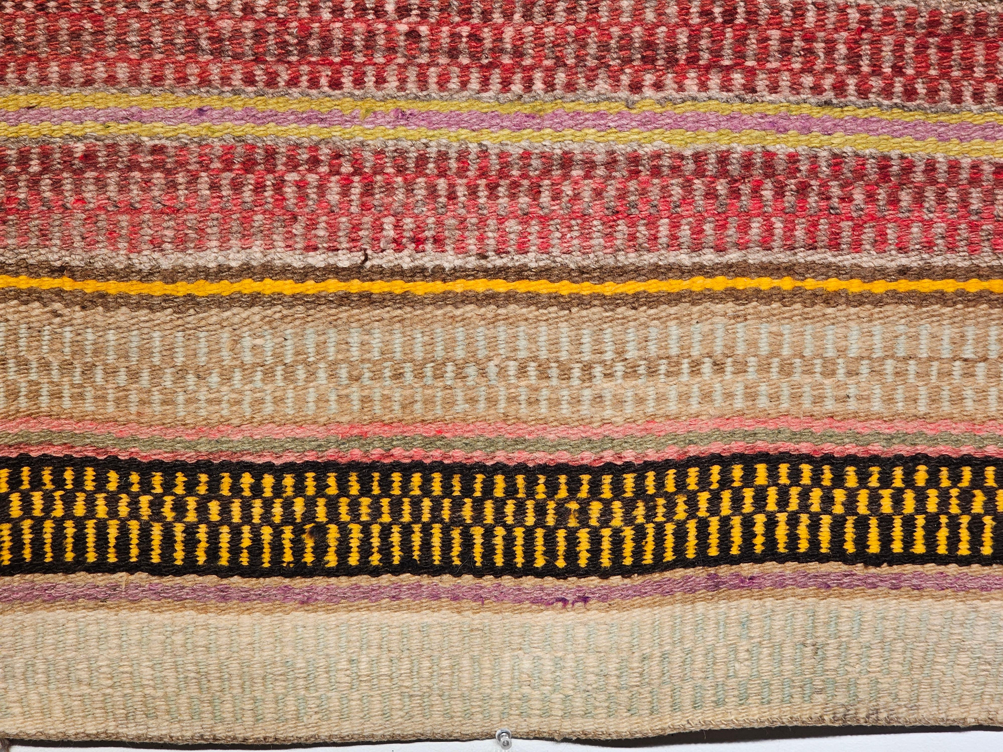  A Navajo saddle blanket in banded design with beautiful natural earth tone colors including red, brown, caramel set on a taupe background separated by narrow bands from the mid 1900s..  The design of this Navajo rug resembles the design of the