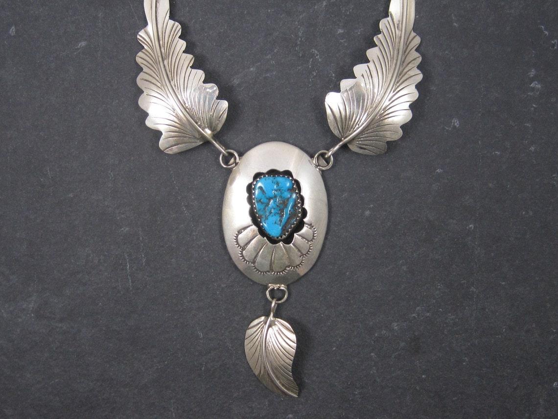 This gorgeous vintage necklace is sterling silver and is the creation of Navajo artist Arnold Maloney.

It features traditional feathers and a natural turquoise in a shadowbox setting.

Measurements: 19 1/2 inches from end to end, 12 inches from