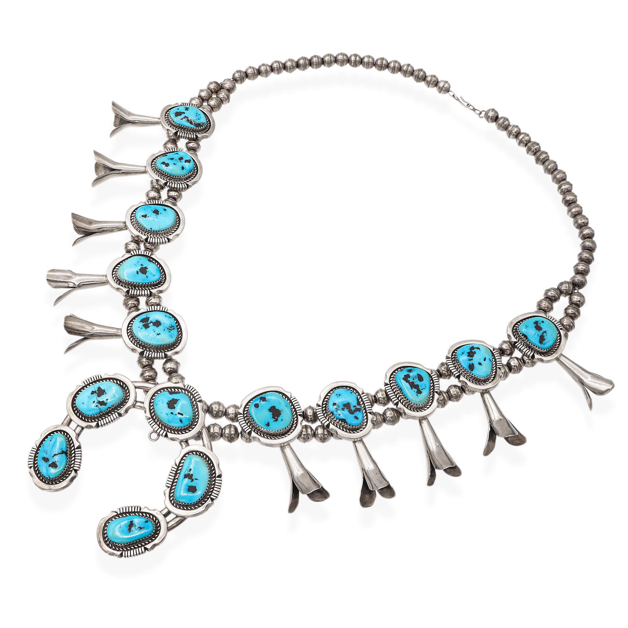 This exquisite vintage Navajo squash blossom necklace is a striking example of traditional Southwestern artistry and cultural heritage. Crafted in sterling silver, the necklace features a series of large, natural turquoise cabochons in vibrant