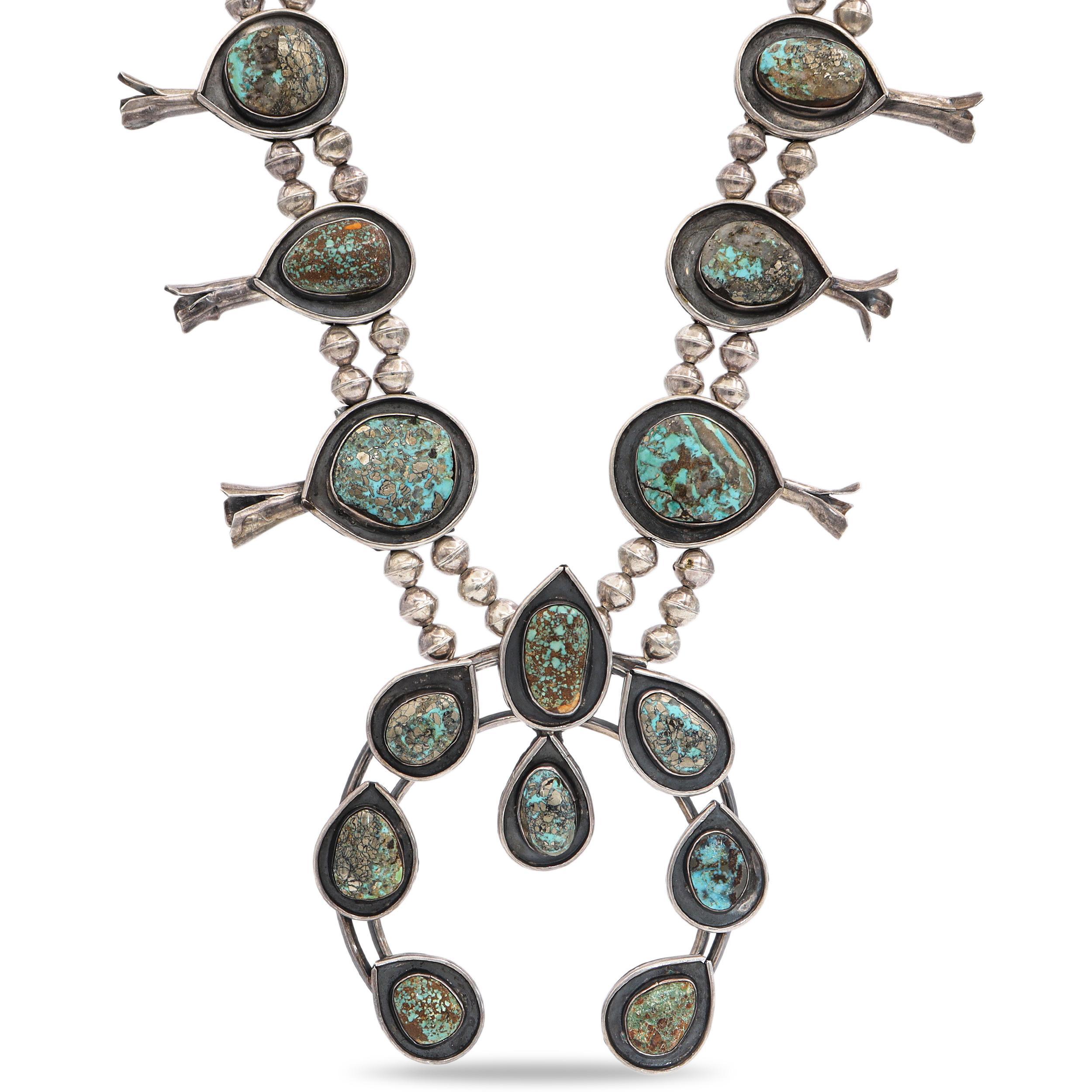 Una straordinaria collana vintage di fiori di zucca in argento Navajo con grandi pietre di turchese naturale e ricchi motivi a matrice. Ogni pietra è incastonata in un castone realizzato a mano e circondato da argento ossidato e perline