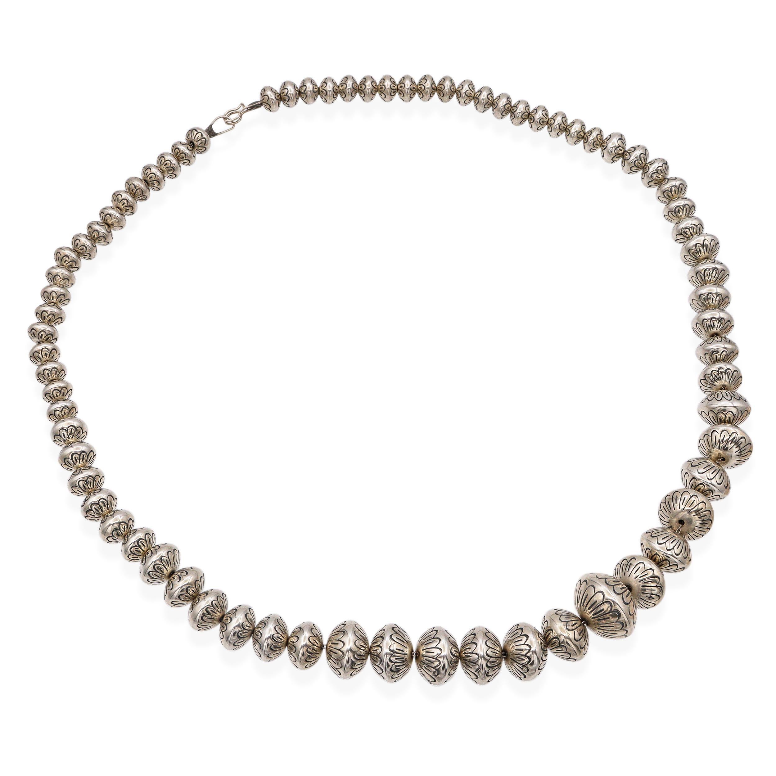 Este collar navajo vintage muestra maravillosamente el arte y la tradición de la orfebrería de los nativos americanos. Hecho a mano en plata de ley, el collar se compone de cuentas de banco huecas graduadas, cada una meticulosamente estampada a mano