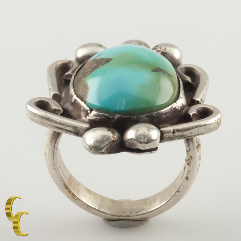 Vintage Native American Navajo silver ring.
Features a bezel-set turquoise in a unique tooled border.
Size: 7.
Approximately 30 mm long.
Metal: 0.925 sterling silver.
Weight: 11.8 grams.