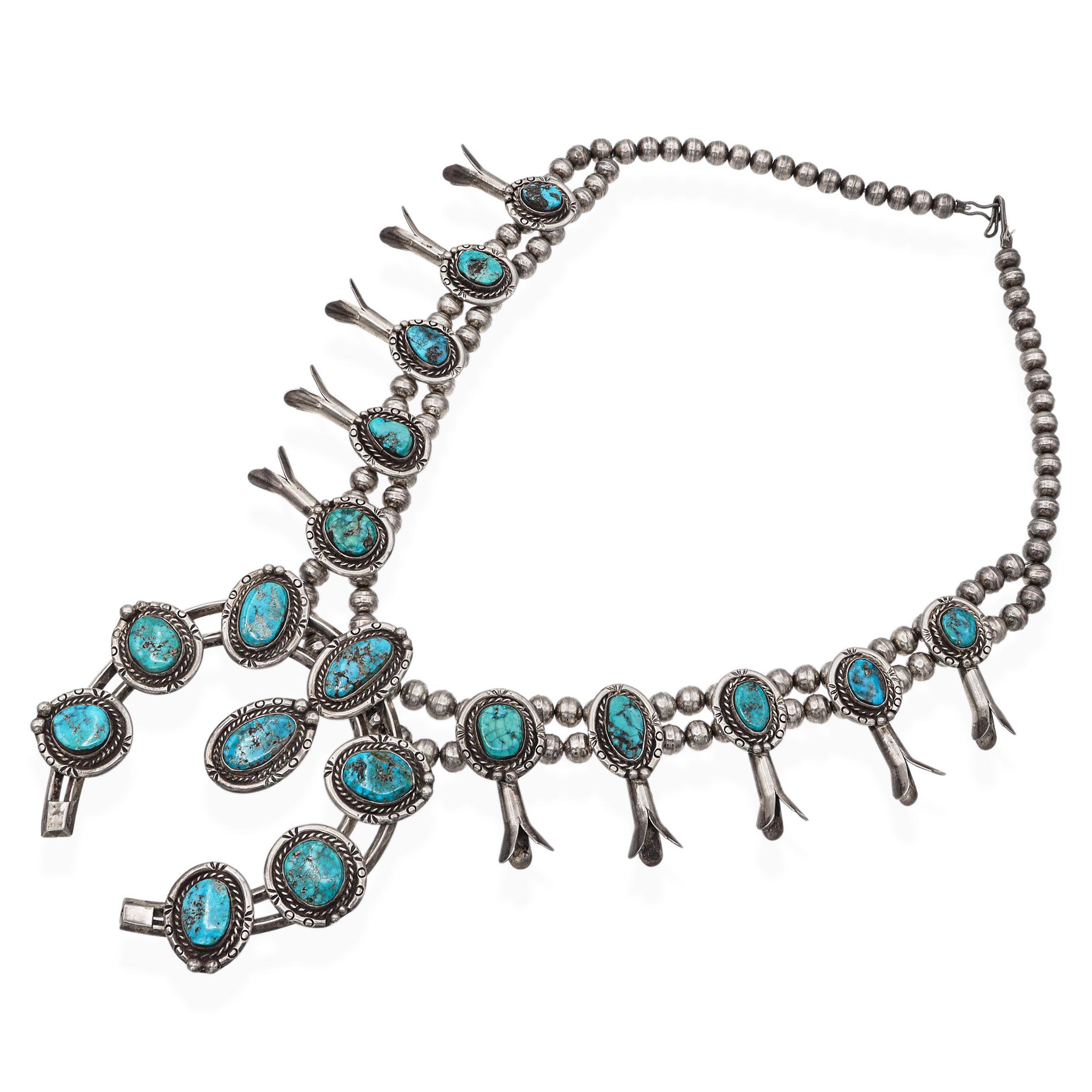 This vintage Navajo squash blossom necklace showcases the artistry and spirit of Native American craftsmanship. Meticulously handcrafted in sterling silver, the necklace features a striking arrangement of hand-drawn silver beads and traditional