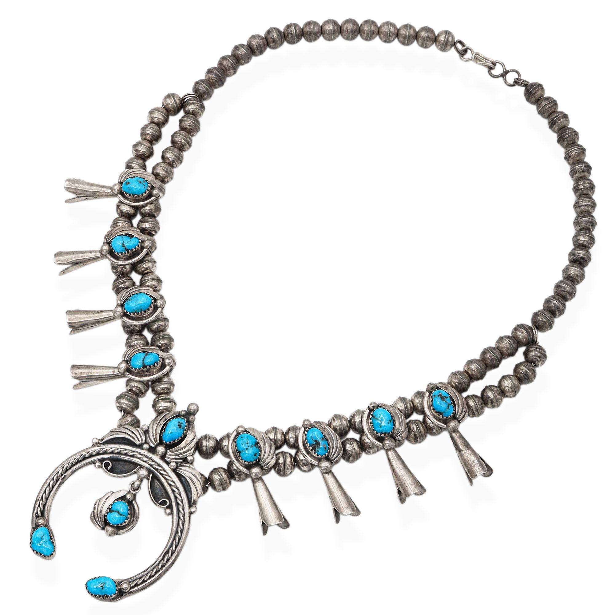 A stunning example of traditional Navajo artistry, this vintage squash blossom necklace is handcrafted in sterling silver and set with vibrant natural turquoise stones. Each blossom features a beautifully bezel-set turquoise cabochon framed by