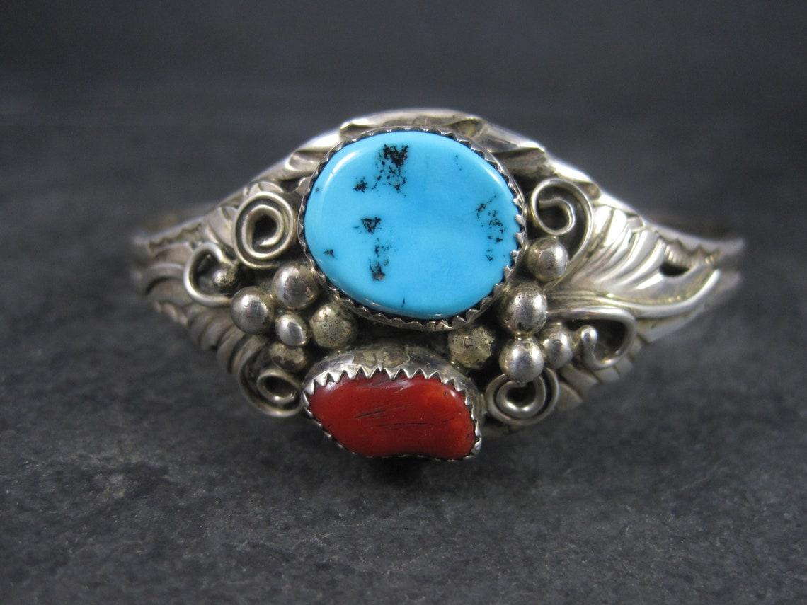 This beautiful cuff bracelet is sterling silver with natural coral and turquoise stones.

Measurements:
The turquoise stone measures 13x15mm.
The coral measures 8x13mm.
The face of the bracelet is 1 1/16 inches wide. The cuff at its narrowest is 1/4