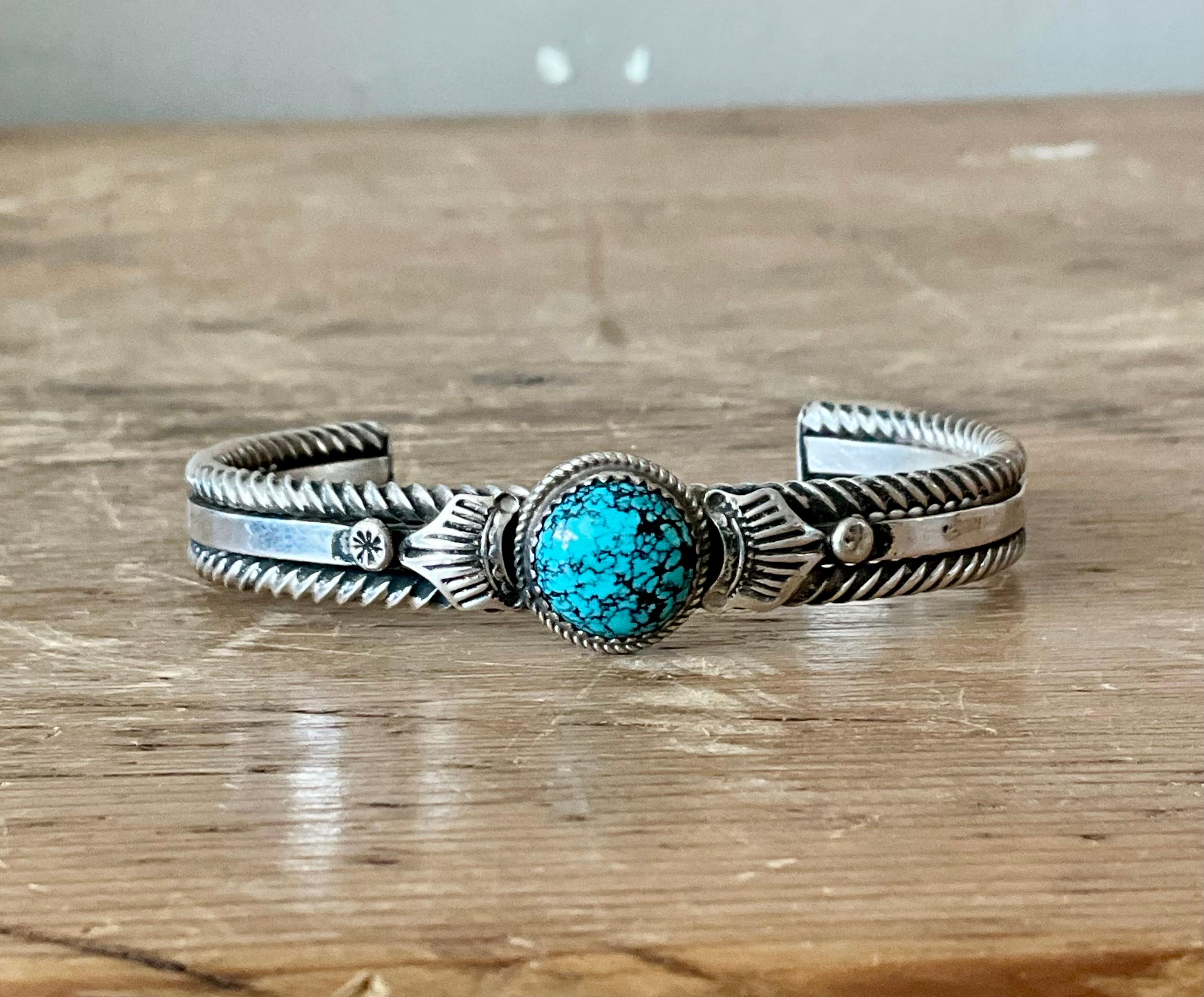 Questo bracciale vintage in argento con turchese Navajo è un esempio di artigianato tradizionale del Sud-Ovest. Realizzato a mano da un abile artigiano Navajo, il bracciale presenta una splendida pietra turchese naturale, ricca di colore e con una