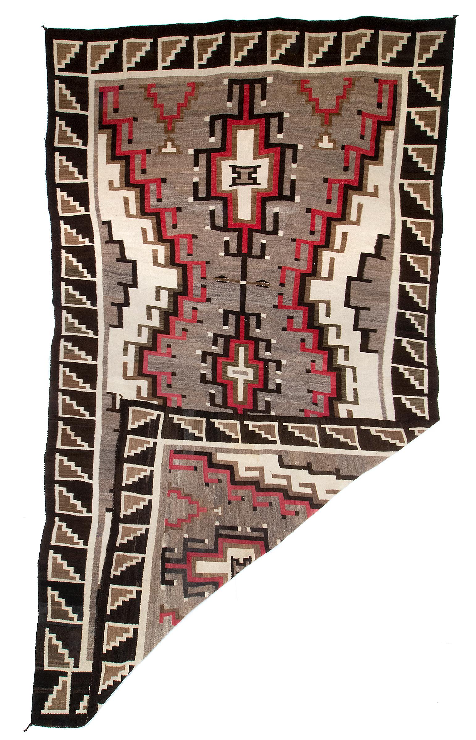 Large vintage Navajo Area Rug weaving from the Hubbell Trading Post in Ganado, Arizona (Southwestern United States). Woven of native hand-spun wool in natural fleece colors of brown/black, ivory/white, grey/brown with aniline dyed red. Hand woven by