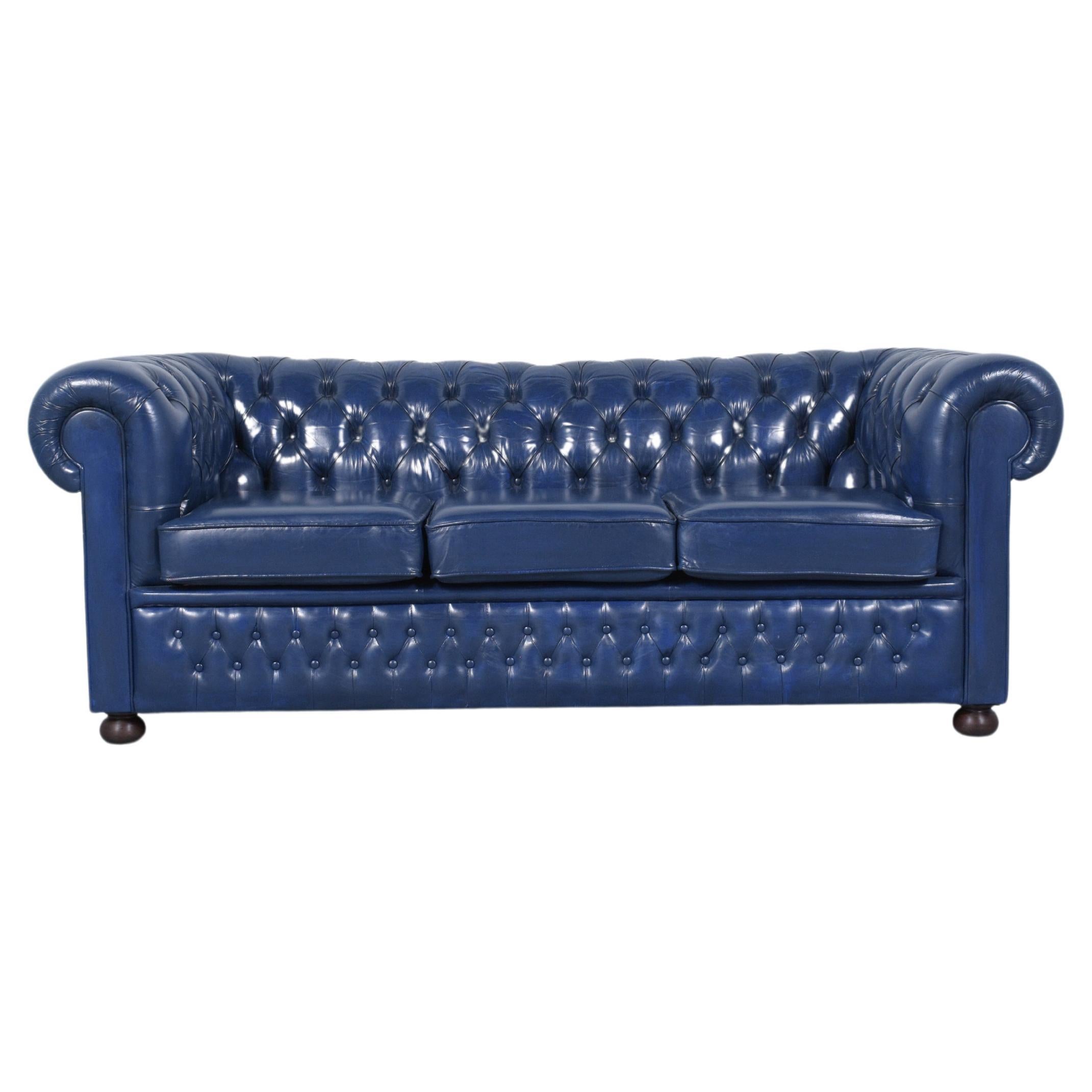 Embrace the timeless elegance of our restored vintage Chesterfield sofa, a classic embodiment of comfort and sophistication. Crafted in the 1970s and revitalized by our experienced craftsmen, this sofa features a solid wood frame and luxurious navy