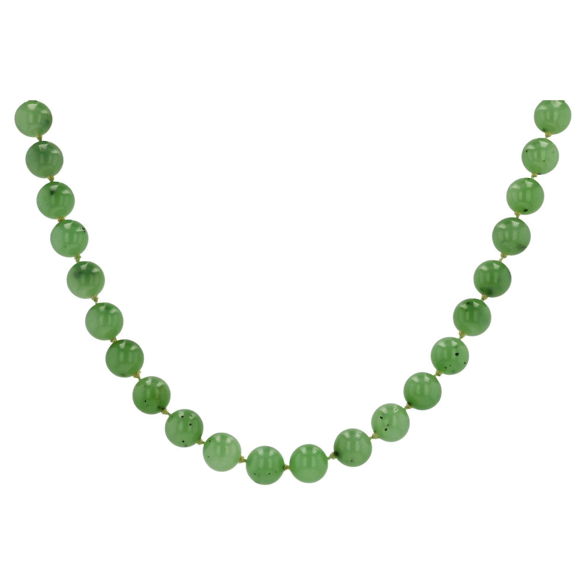 A 1960s vintage signed Gump's Siberian nephrite jade necklace, with generous length and vibrance. These beautiful, untreated jade beads are a translucent light chartreuse green. A bezel set oval cabochon Jade adds a subtle finishing touch to the 14k