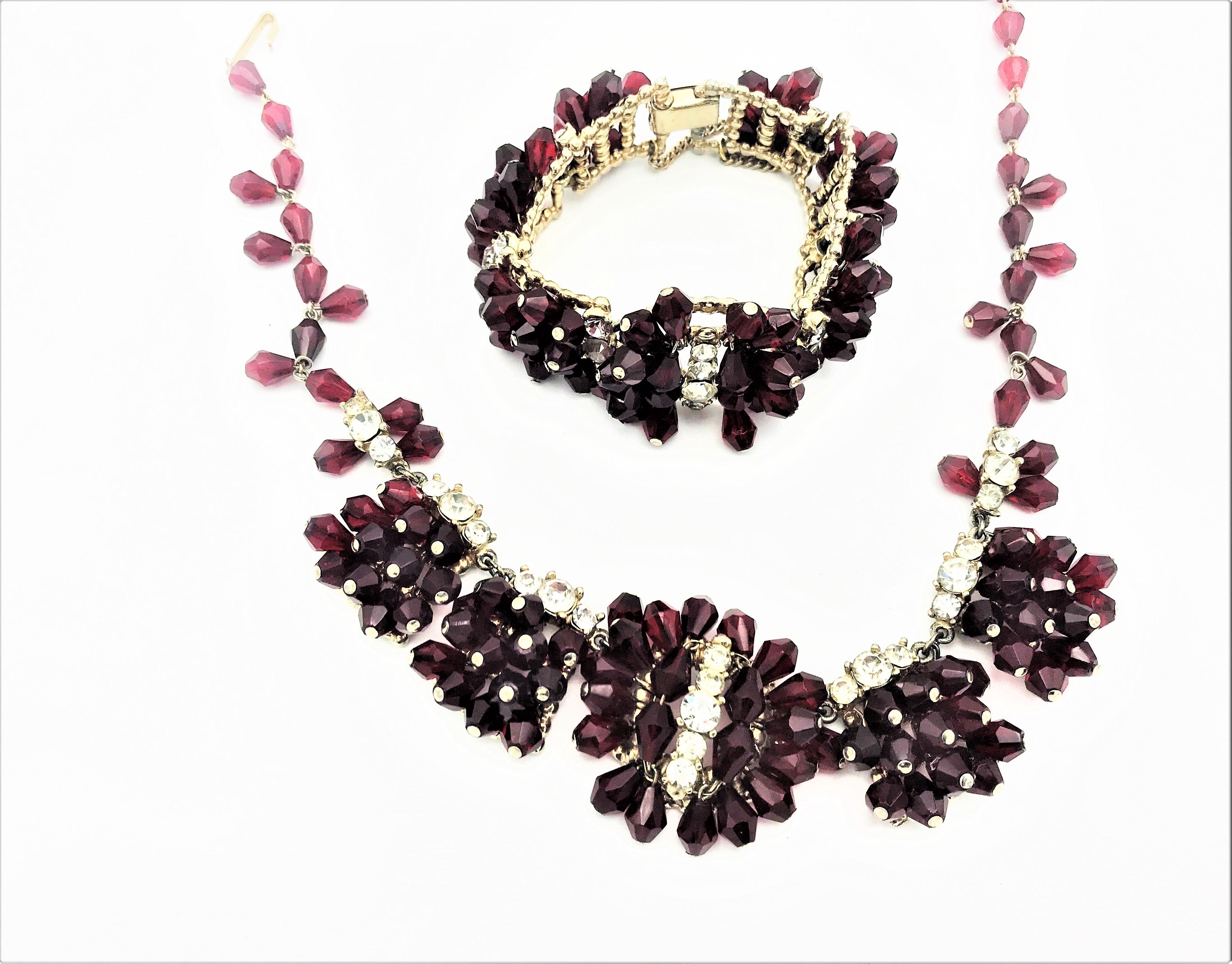 Necklace with matching bracelet made of red cut rhinestones and strass. The chain consists of 5 individual links which are decorated with rhinestones. The bracelet also consists of 6 moving parts, red cut rhinestones and clear rhinestones. The clear