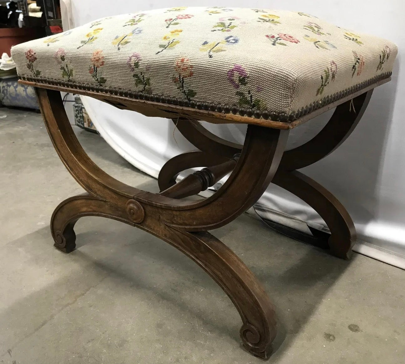 Vintage neoclassical style curule bench covered in multi toned floral needlepoint upholstery and nailheads.
Bench, needlepoint bench, ottoman, footstool, floral bench, vintage bench, stool.