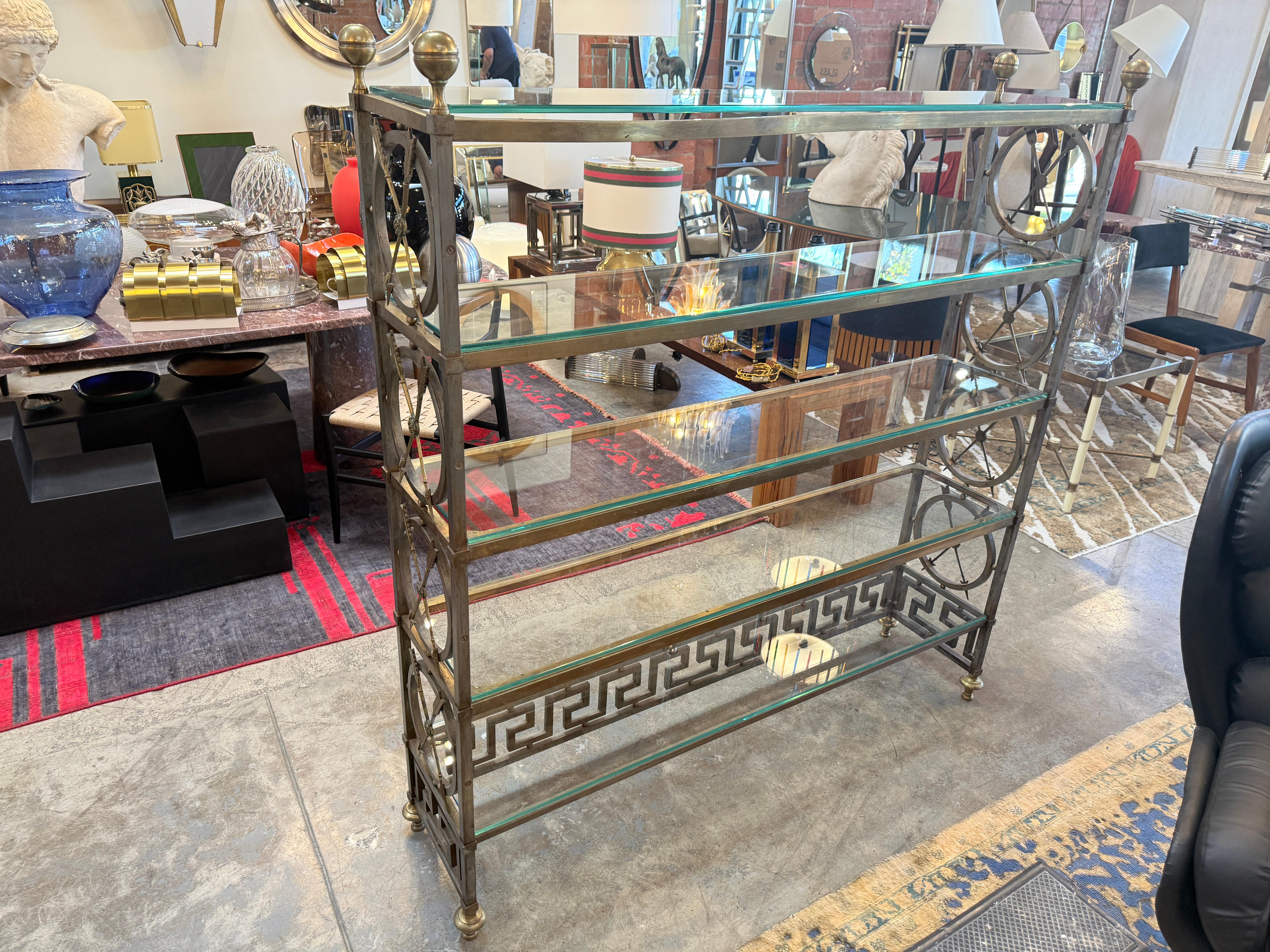 Auffällige Etagere im neoklassizistischen Stil mit einem Messingrahmen mit dekorativen griechischen Schlüsseln und kreisförmigen Motiven, gepaart mit vier Glasböden. Das Design verbindet Eleganz und Symmetrie mit fein gegossenen Messingakzenten wie