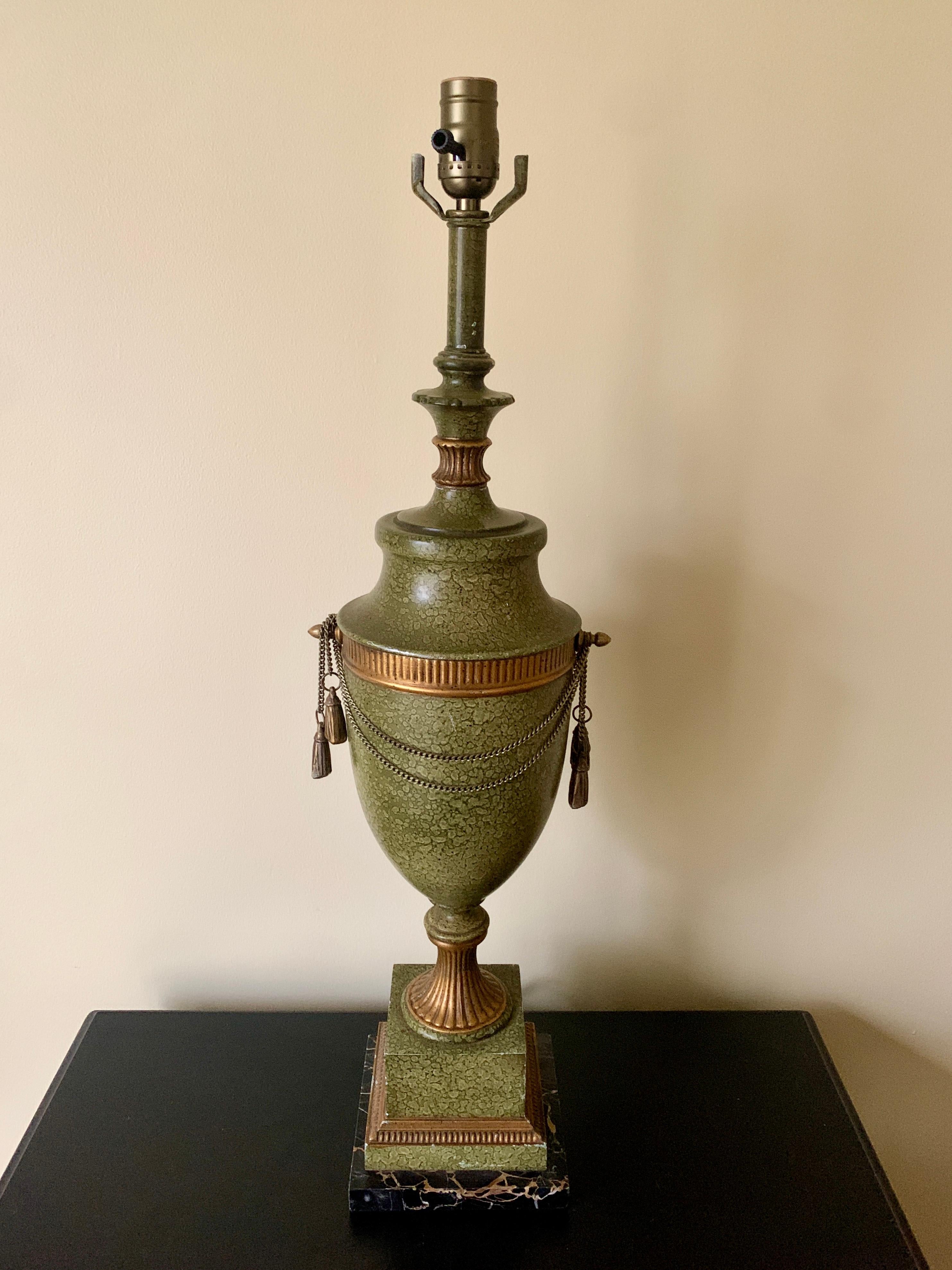 A stunning neoclassical or Hollywood Regency style urn form green tole table lamp

USA, Circa 1960s

Tole painted in an olive green faux marble pattern, with gold gilt details, brass swagger chains with tassels, and black & tan marble